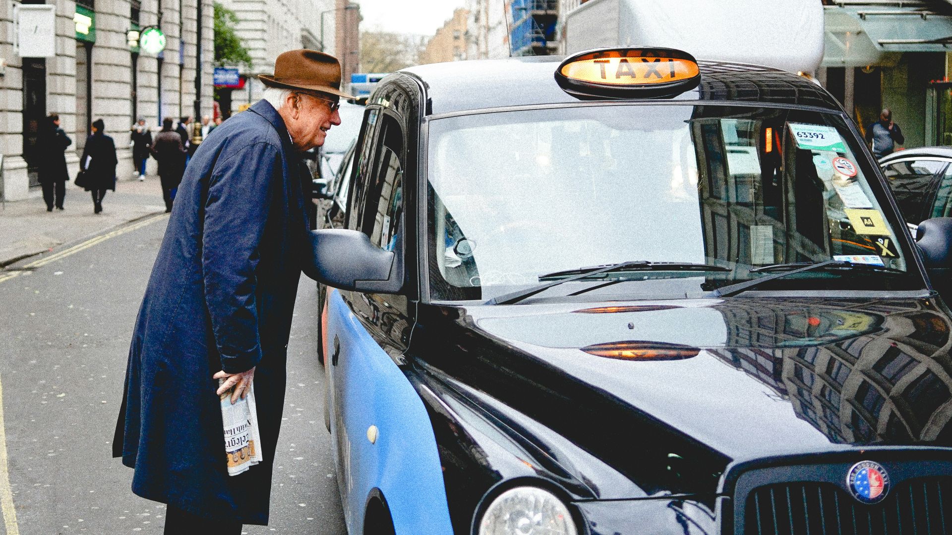 man talking through taxi car mirror during daytime