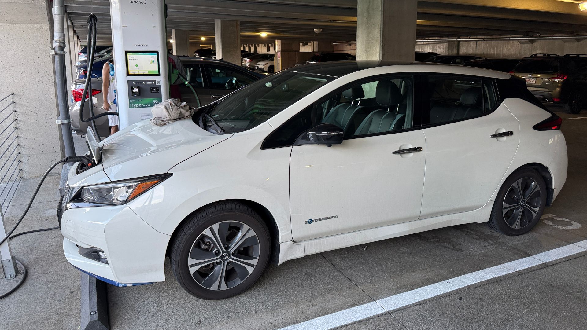 A Nissan Leaf electric car charging at an Electrify America station in a parking garage in Assembly Square in Somerville, Massachusetts
