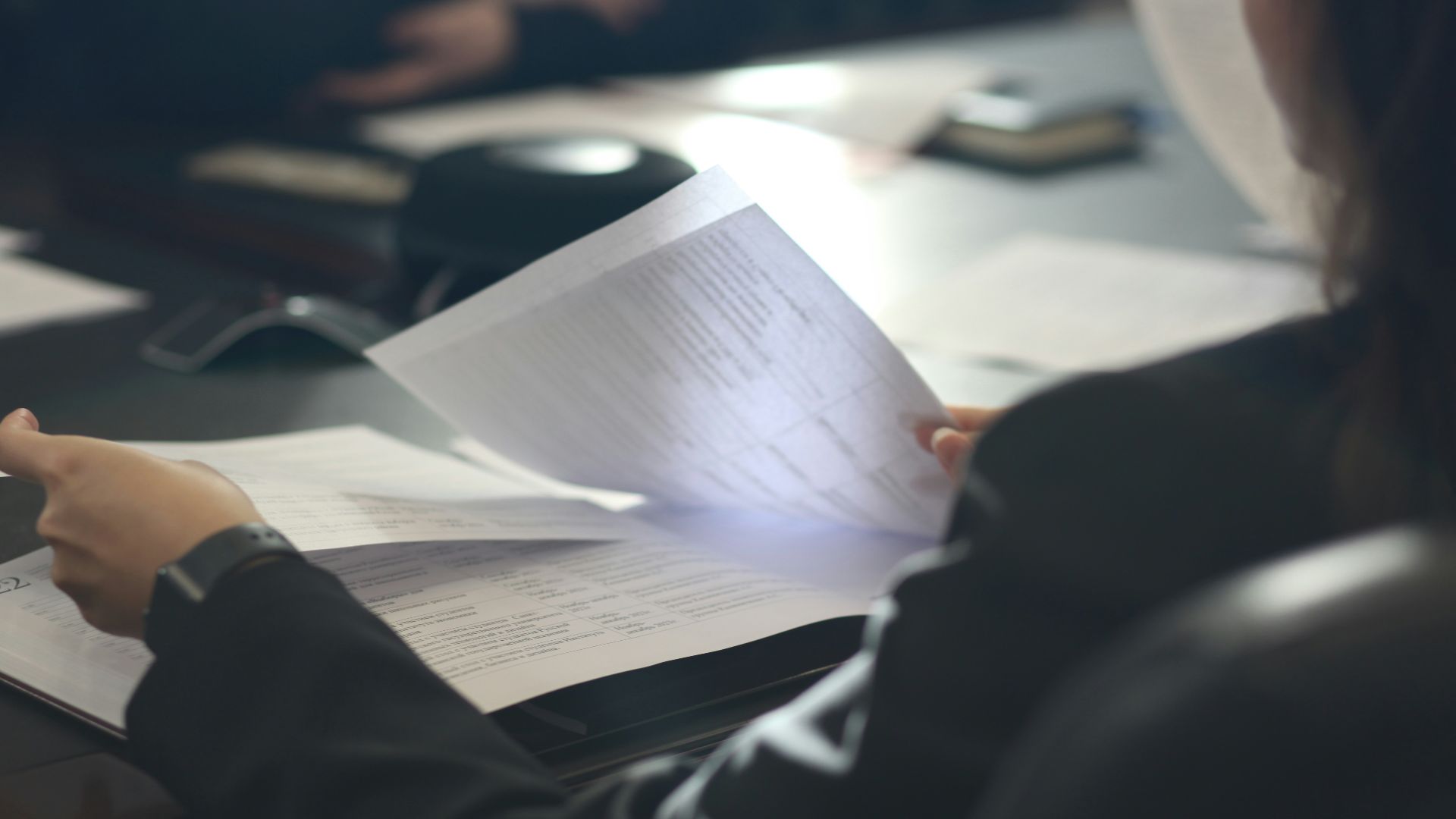 a woman sitting at a table reading a paper