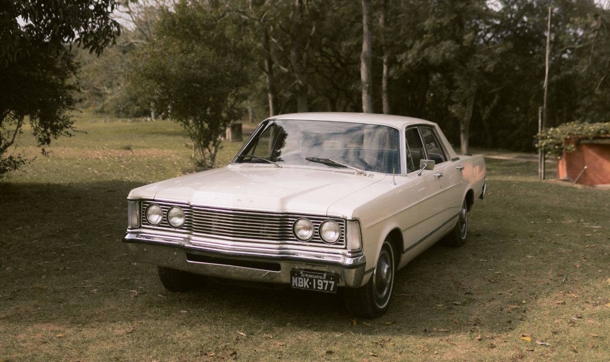 Classic white car parked outdoors amidst lush greenery and trees