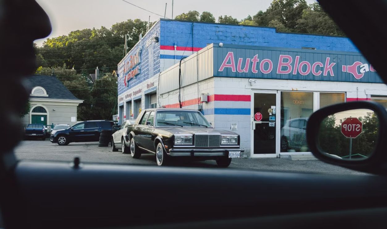 View of an auto repair shop exterior with a classic car in the parking lot