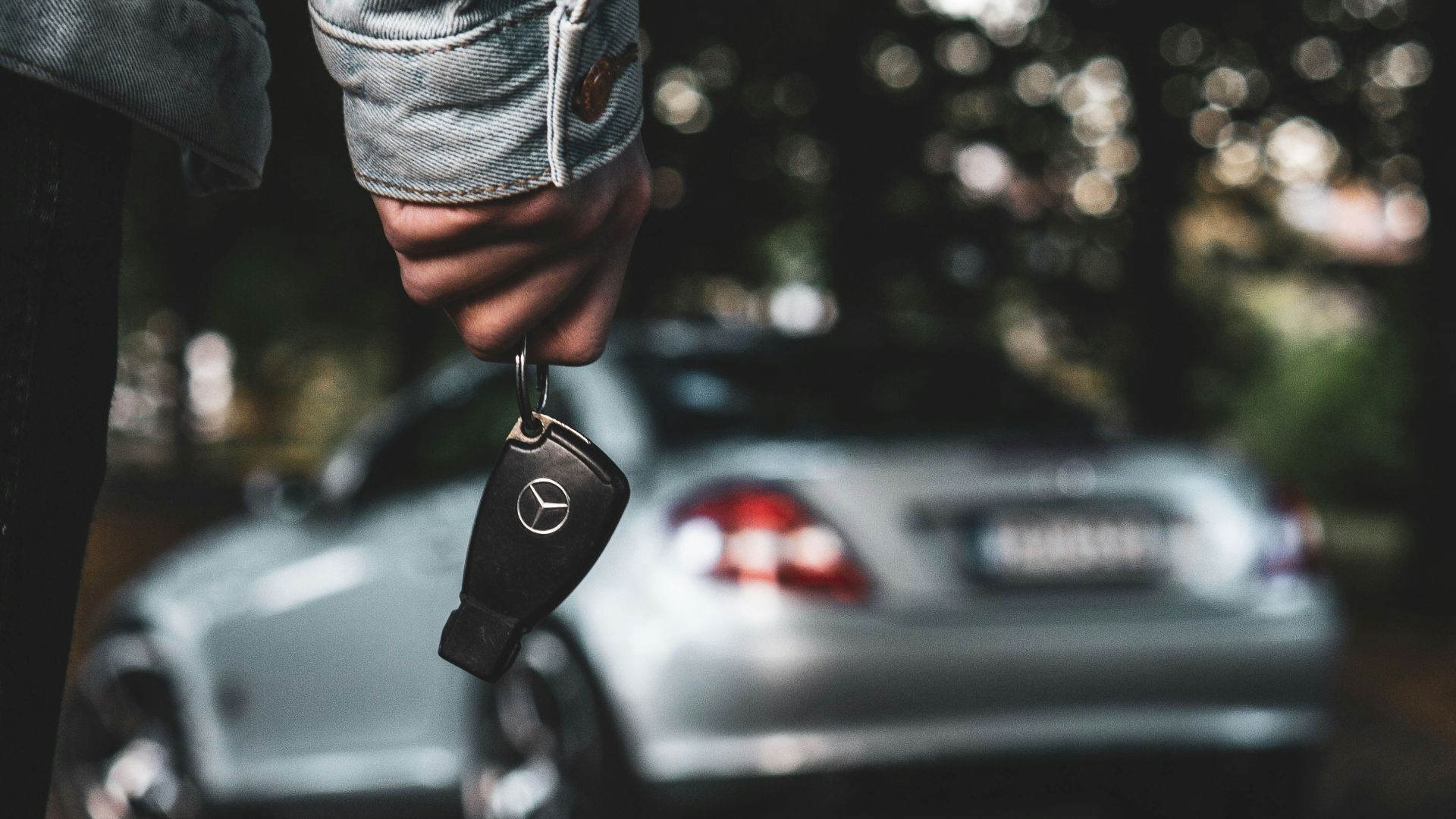 a person holding a car key next to a silver car
