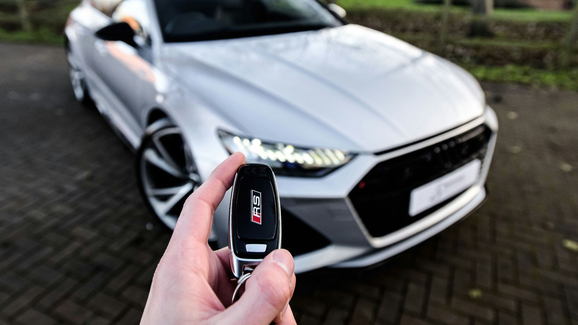 a person holding a car key in front of a silver car