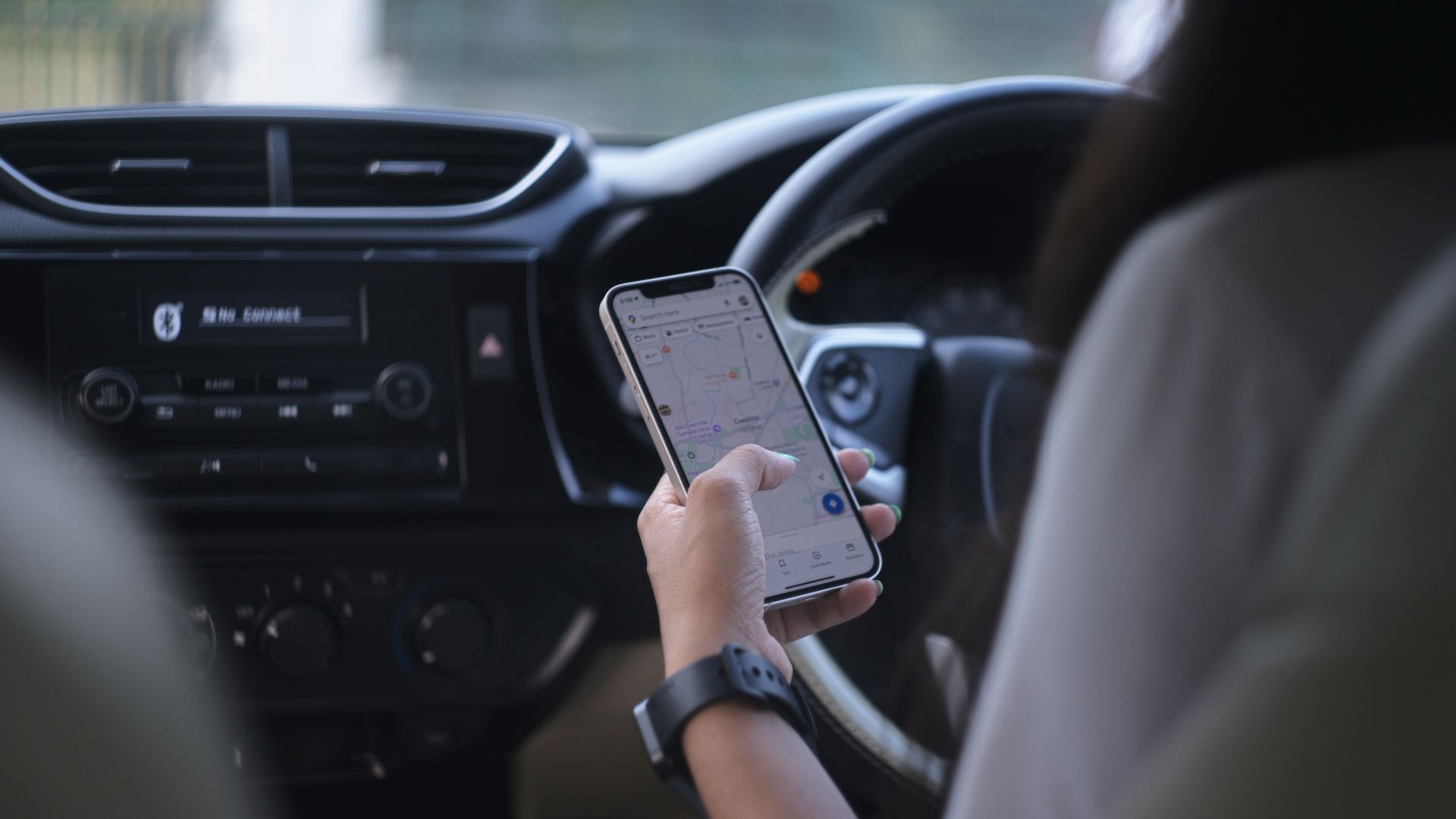 A woman holding a cell phone while driving a car