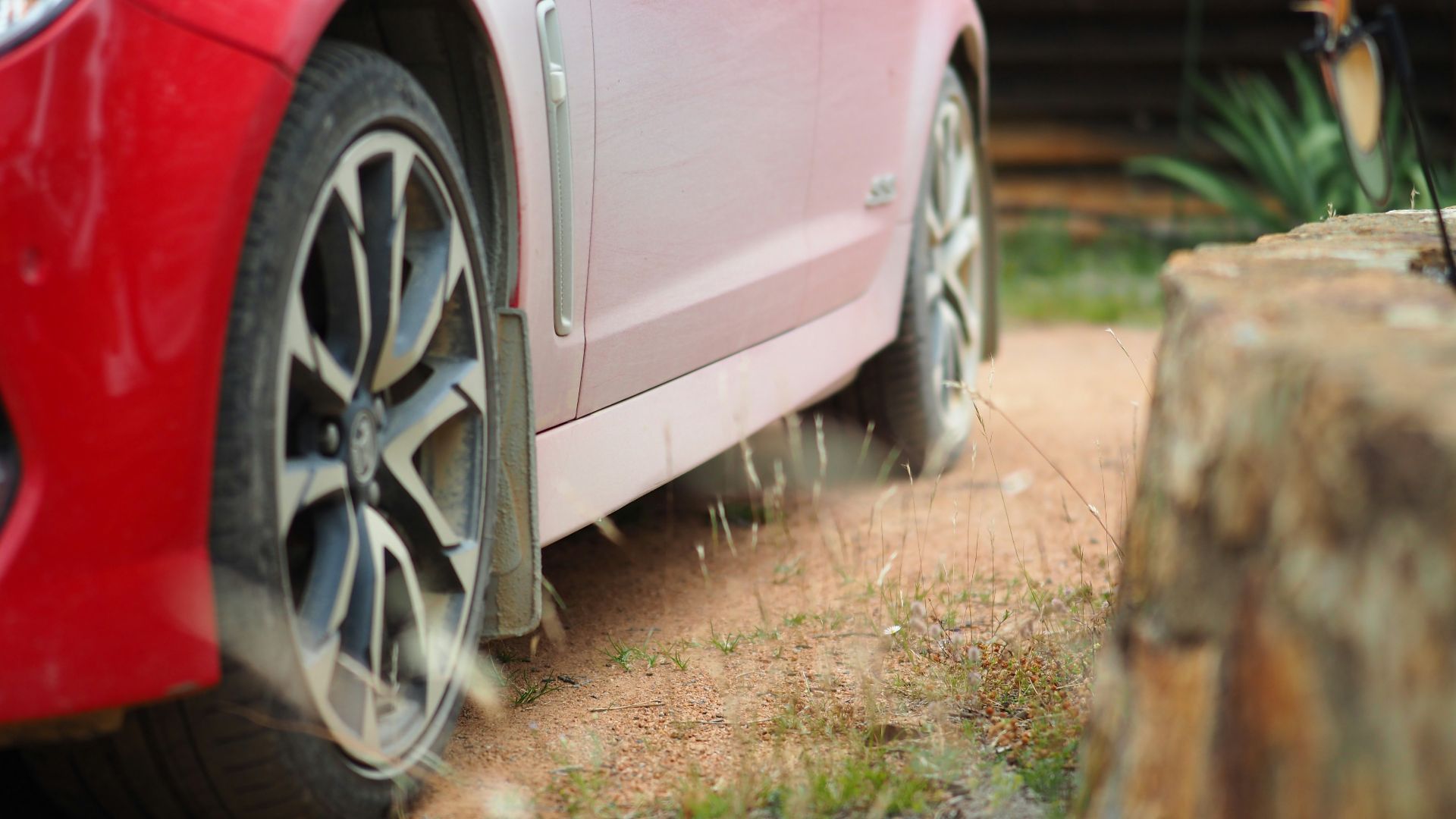 red car parked near brown wooden fence