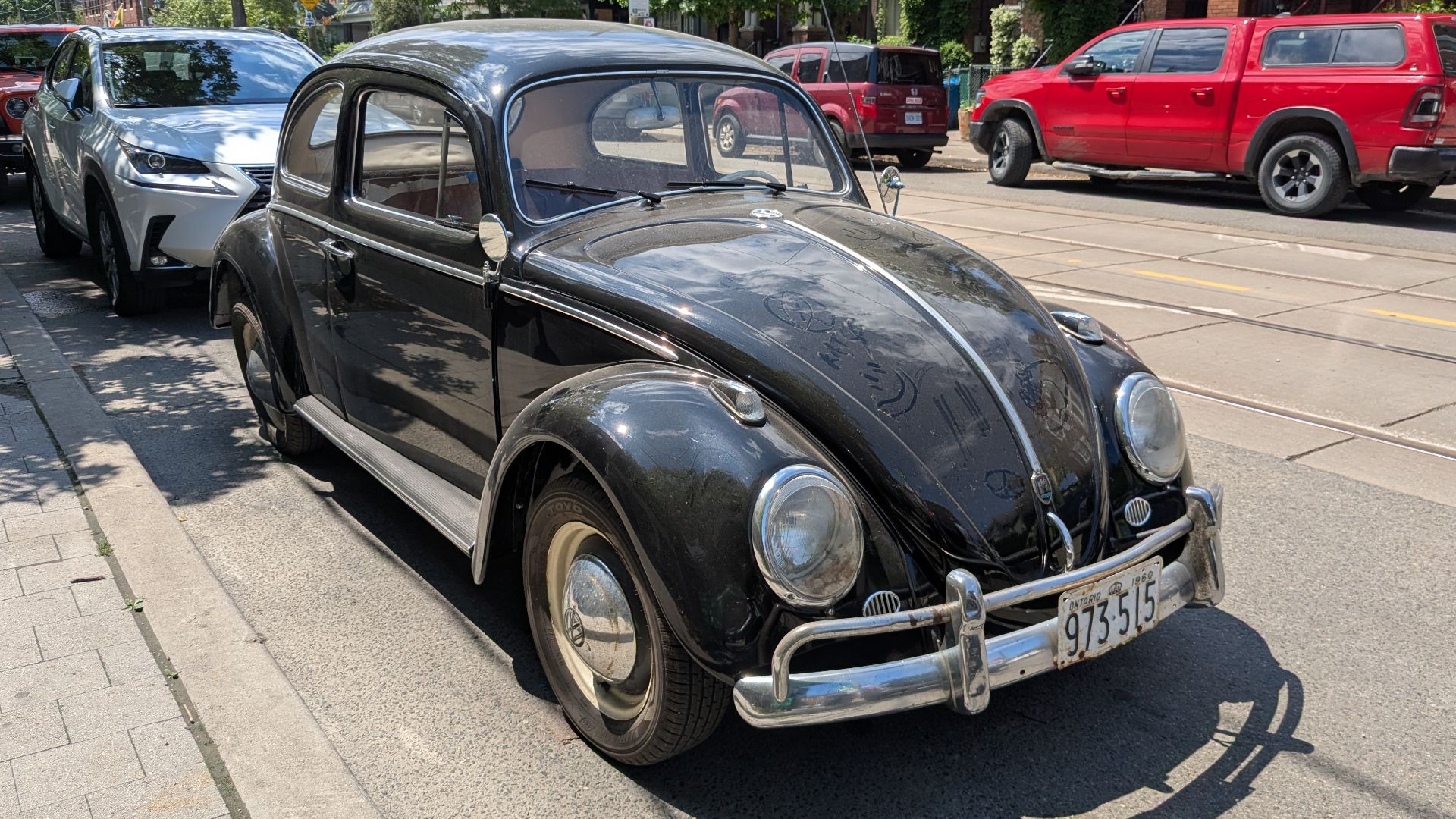 Front three-quarters view of a black Volkswagen Beetle with a 1960 Ontario licence plate parked on Roncesvalles Avenue in Toronto in June 2026