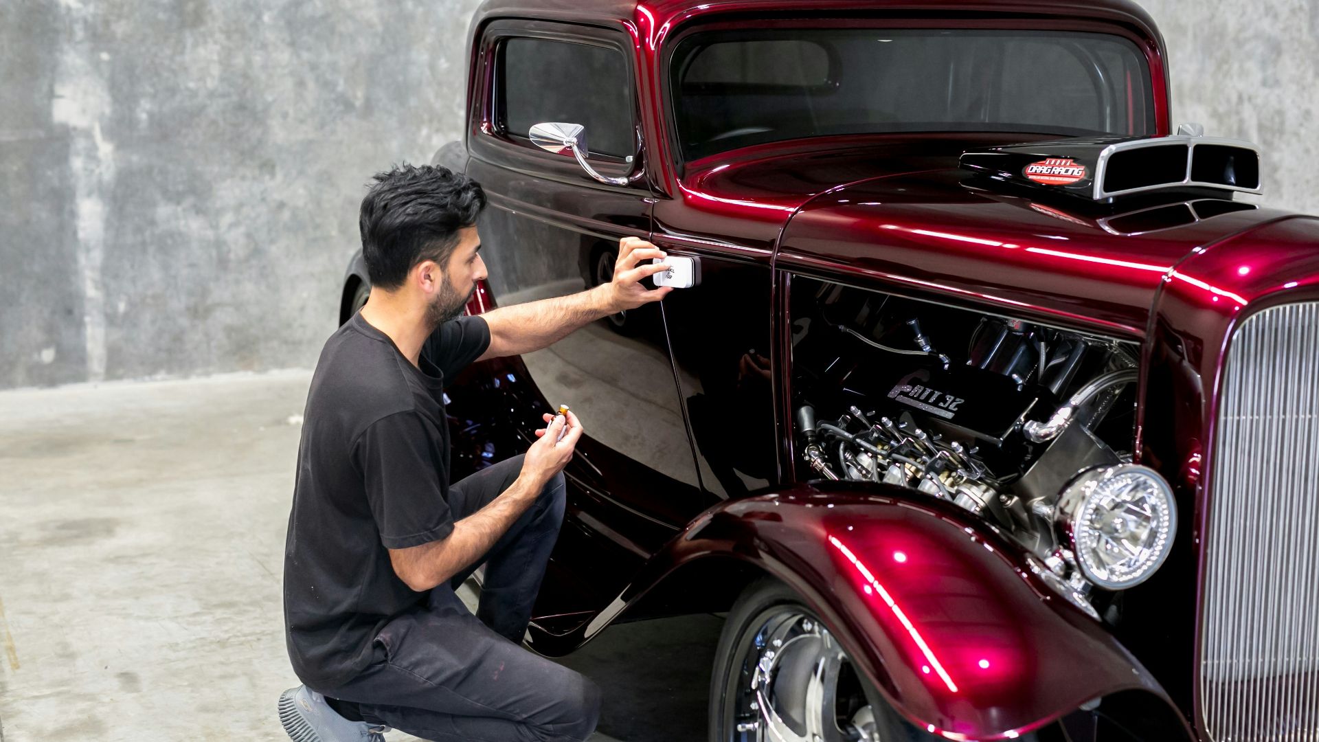 Man takes a photo of a shiny, red hot rod