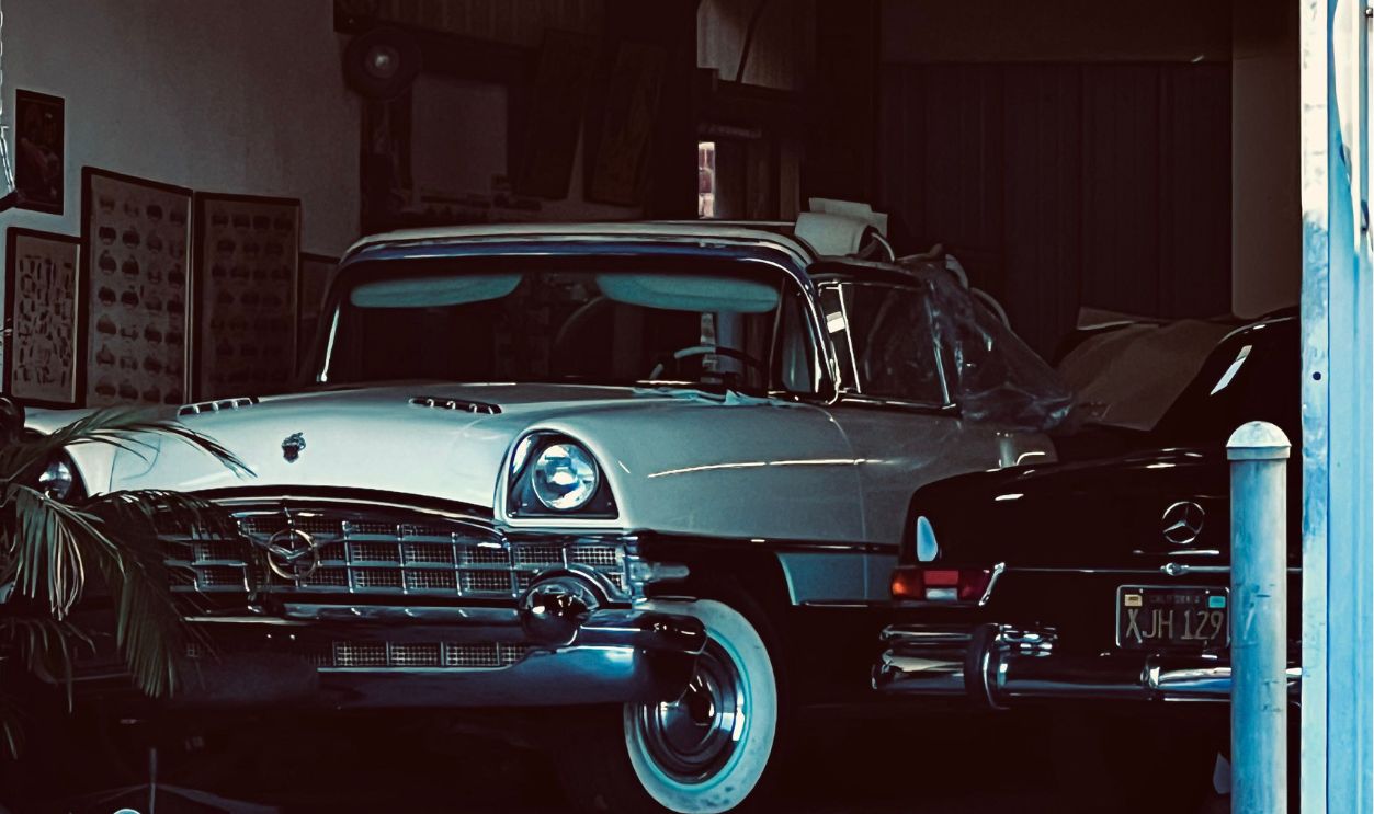 A vintage car parked in a garage with graffiti on the door, showcasing retro automotive charm