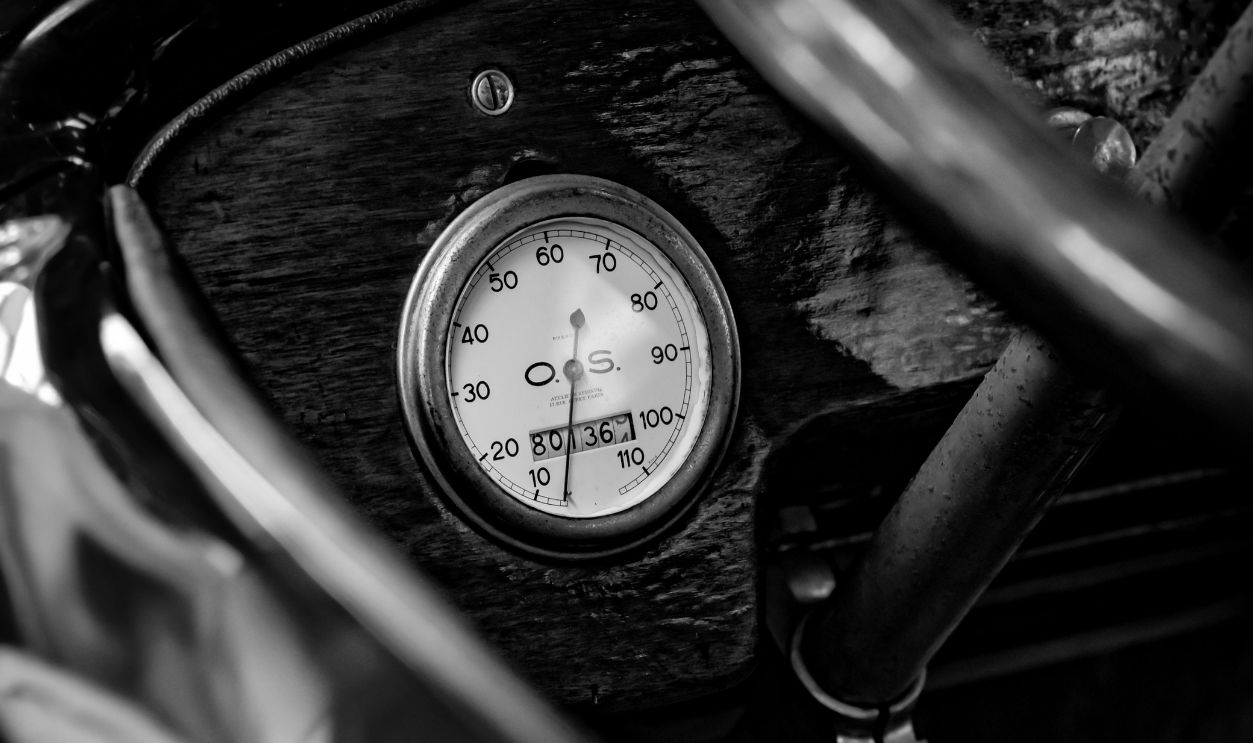 Close-up of a vintage car speedometer with elegant dials and shadow play in monochrome