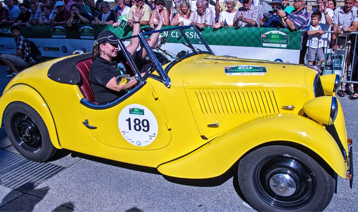 A vibrant yellow vintage convertible car featured at the Sachsen Classic rally in Leipzig, Germany