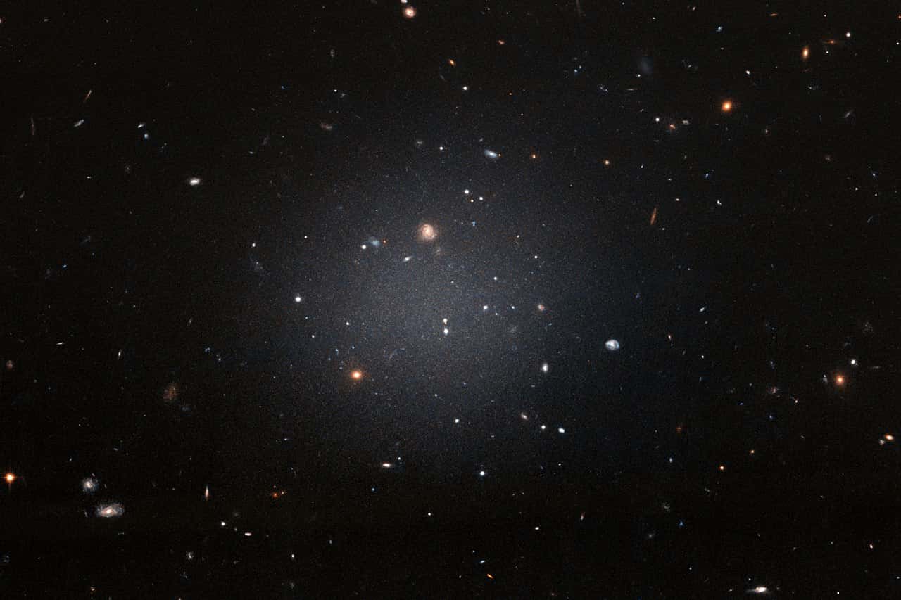 A ghostly galaxy lacking dark matter, distant galaxies behind it