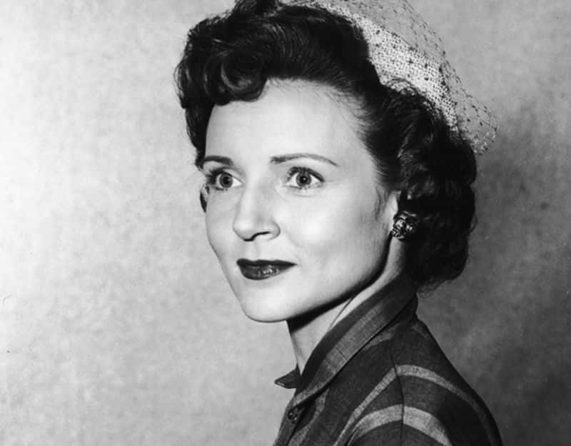 A headshot portrait of American actor Betty White wearing a veiled hat