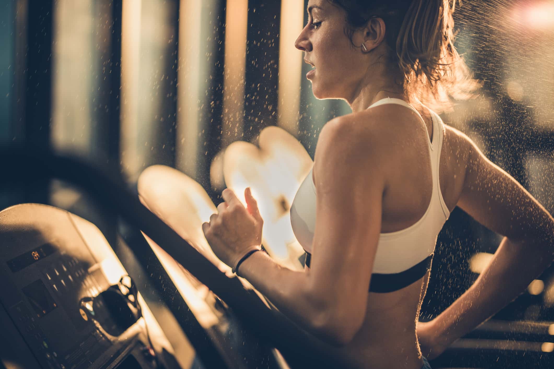 Sweaty woman running on treadmill during sports training in a gym