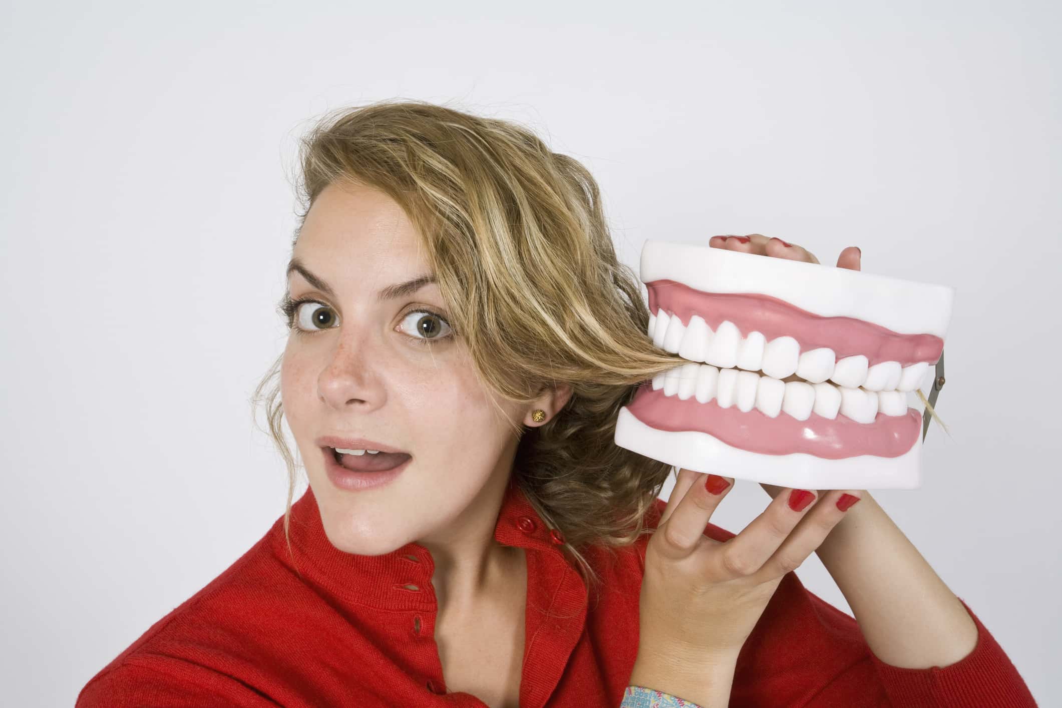 Model wearing a red shirt holding a large jaw biting her hair