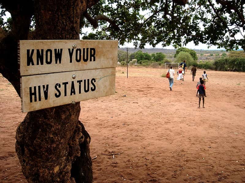 Photo of a Sign: Know your HIV status hanging on a tree in Zambia