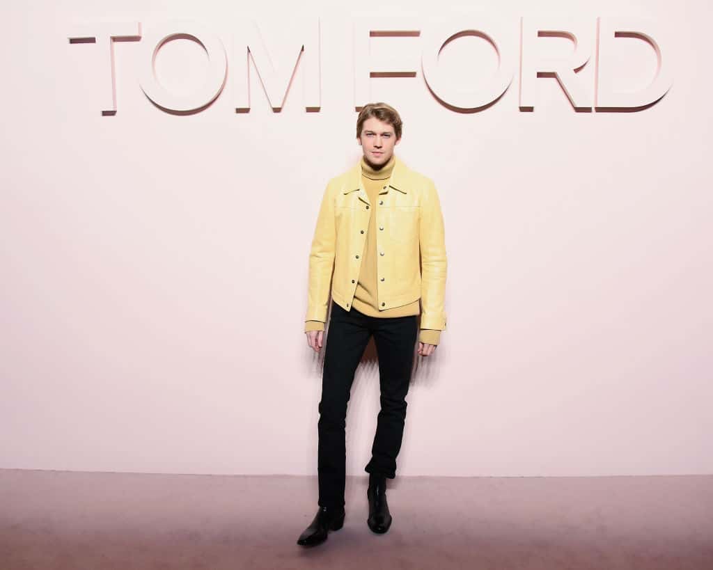 Joe Alwyn attends the Tom Ford New York Fashion Week in New York City, wearing yellow jacket, black pants, facing the camera