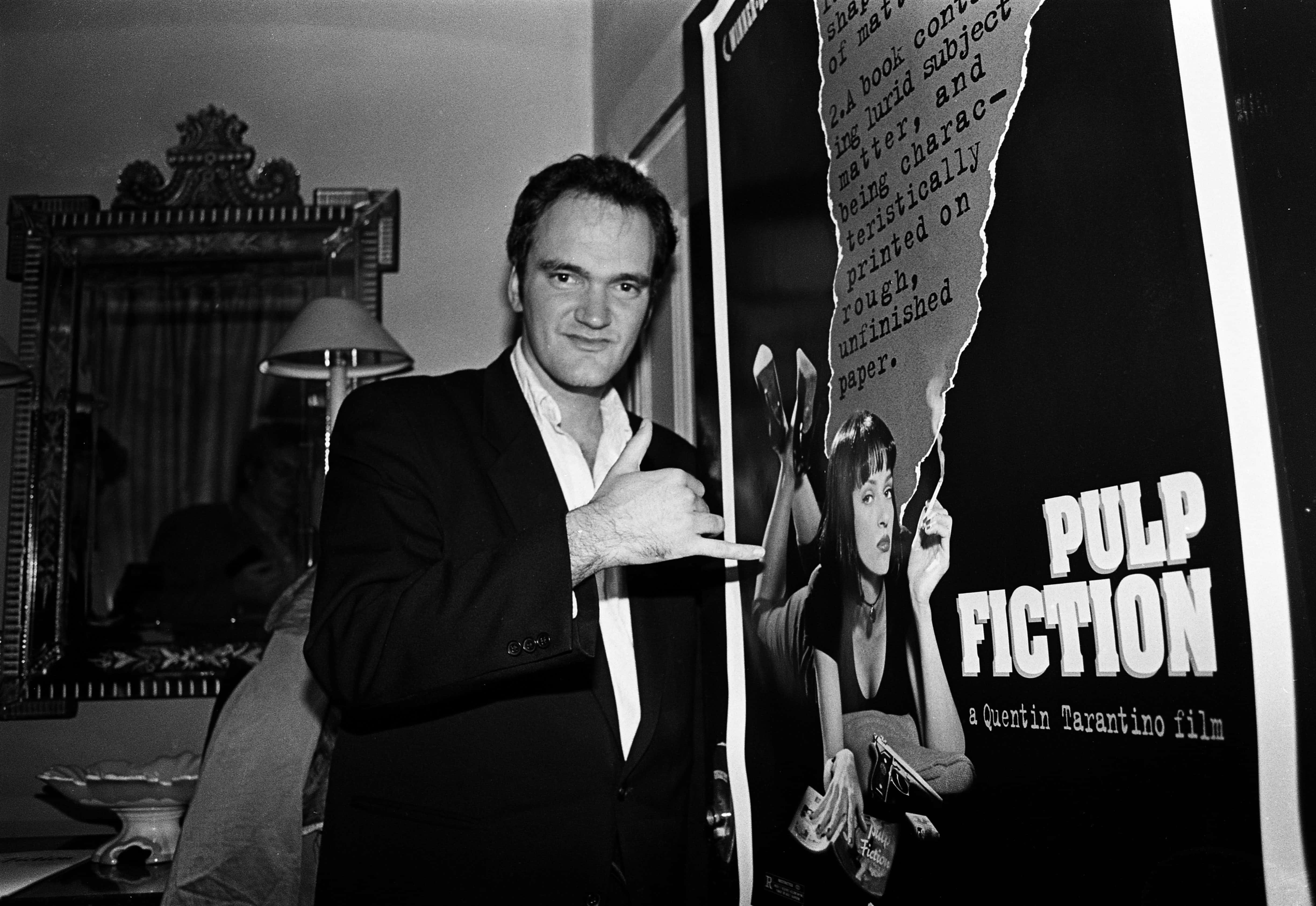 Director Quentin Tarantino standing by a poster for his film 'Pulp Fiction' - 1994