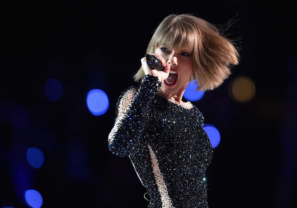 Singer Taylor Swift performs onstage during The GRAMMY Awards at Staples Center, wearing dark dress, holding a microphone
