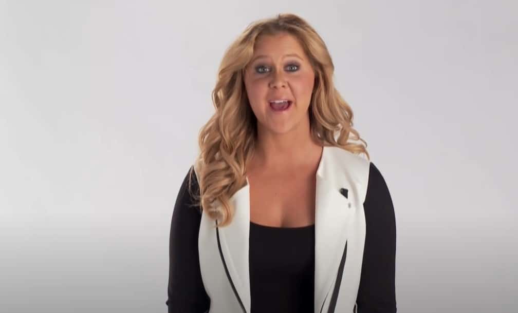 Amy Schumer in black top speaking at her show 