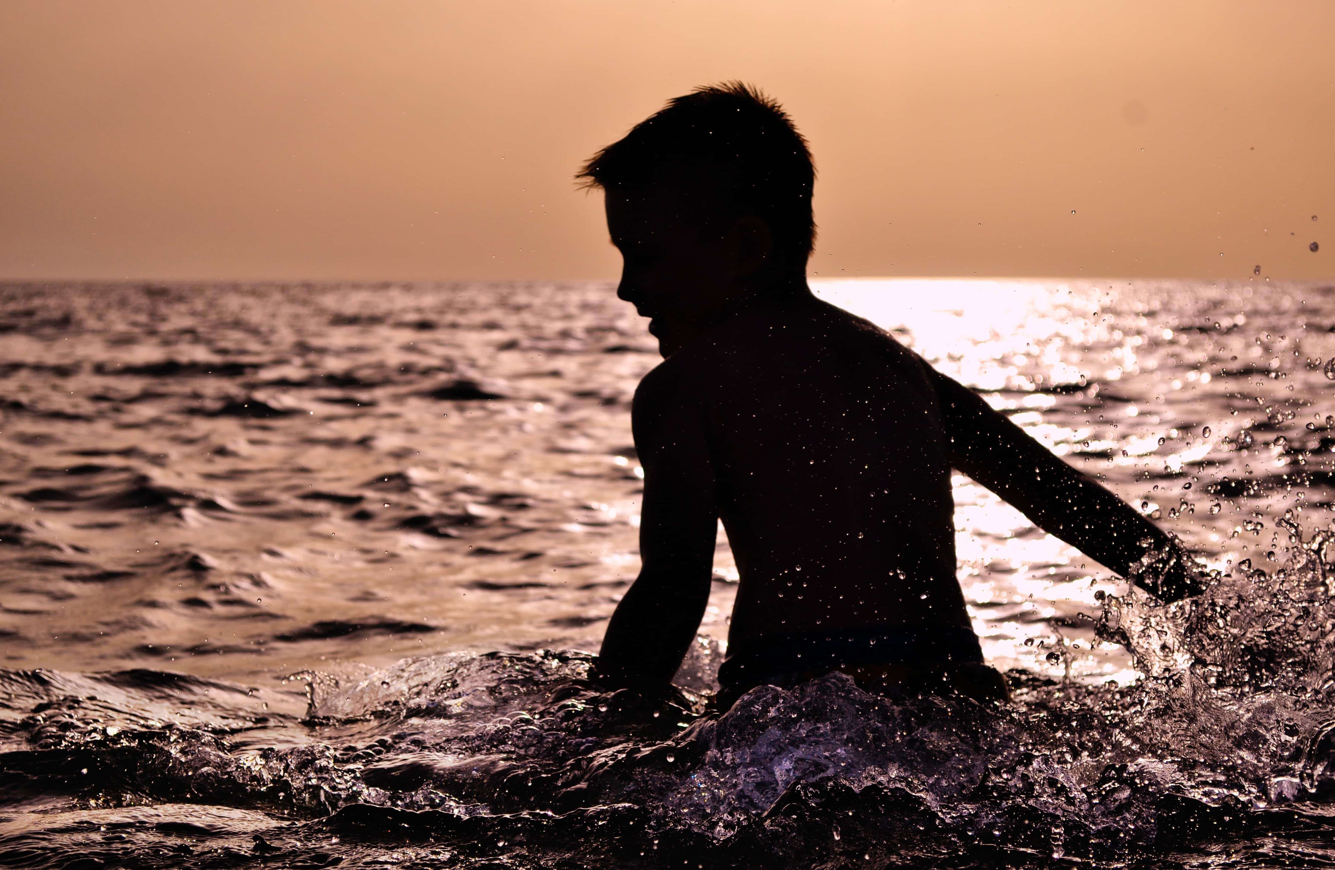Silhouette of Boy in Water on a sunset