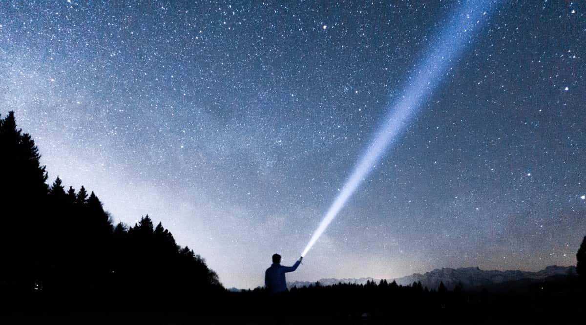 silhouette of man with a flashlight in his hand stargazes