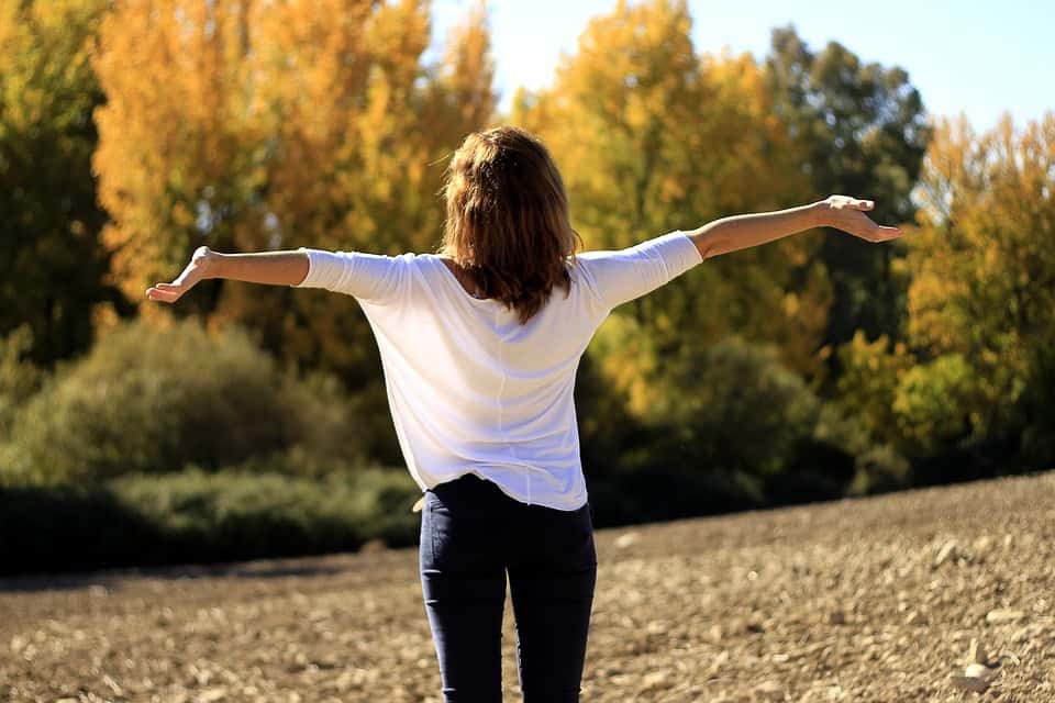Woman standing in the field with spread arms