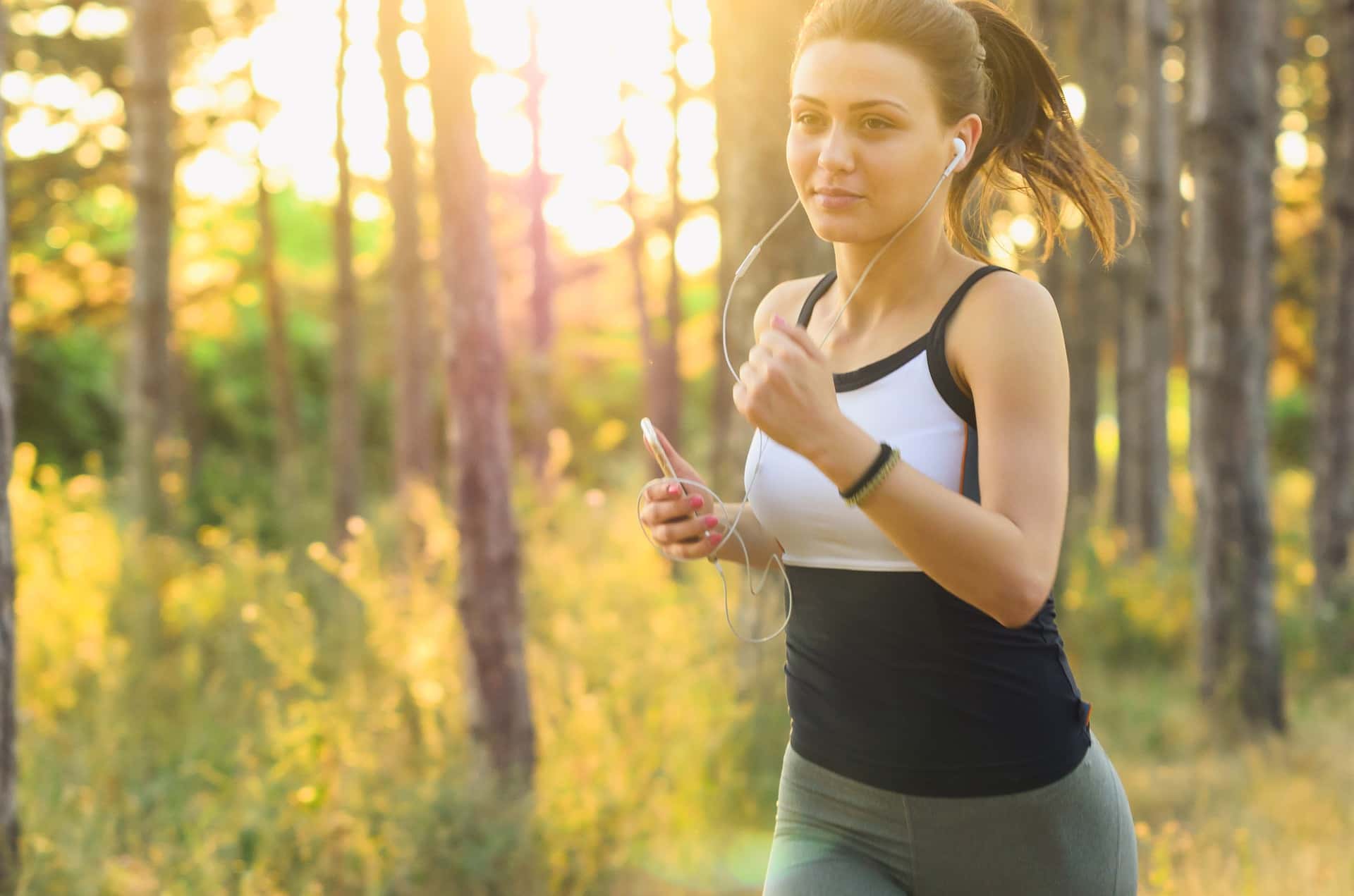 young woman wearing a sports outfit with headphones jogging