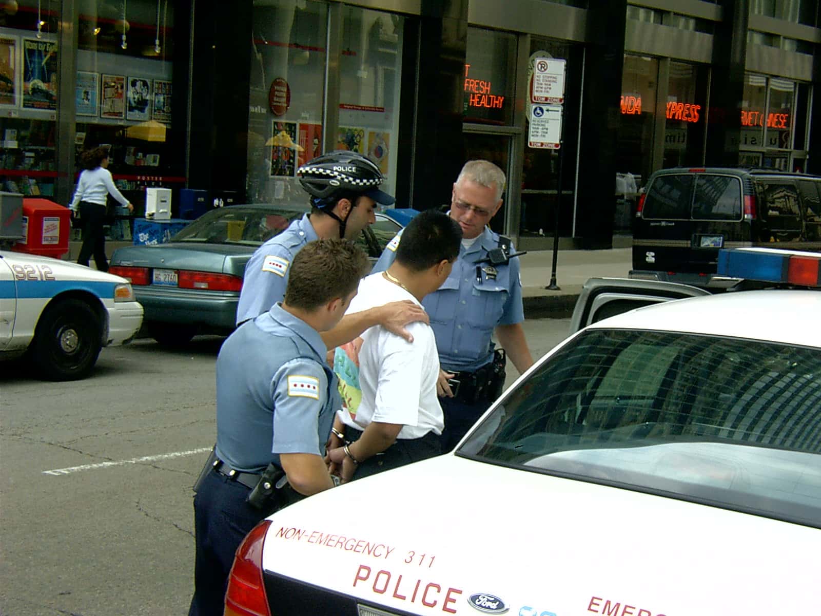 Photo of a man being arrested and packed into a patrol car