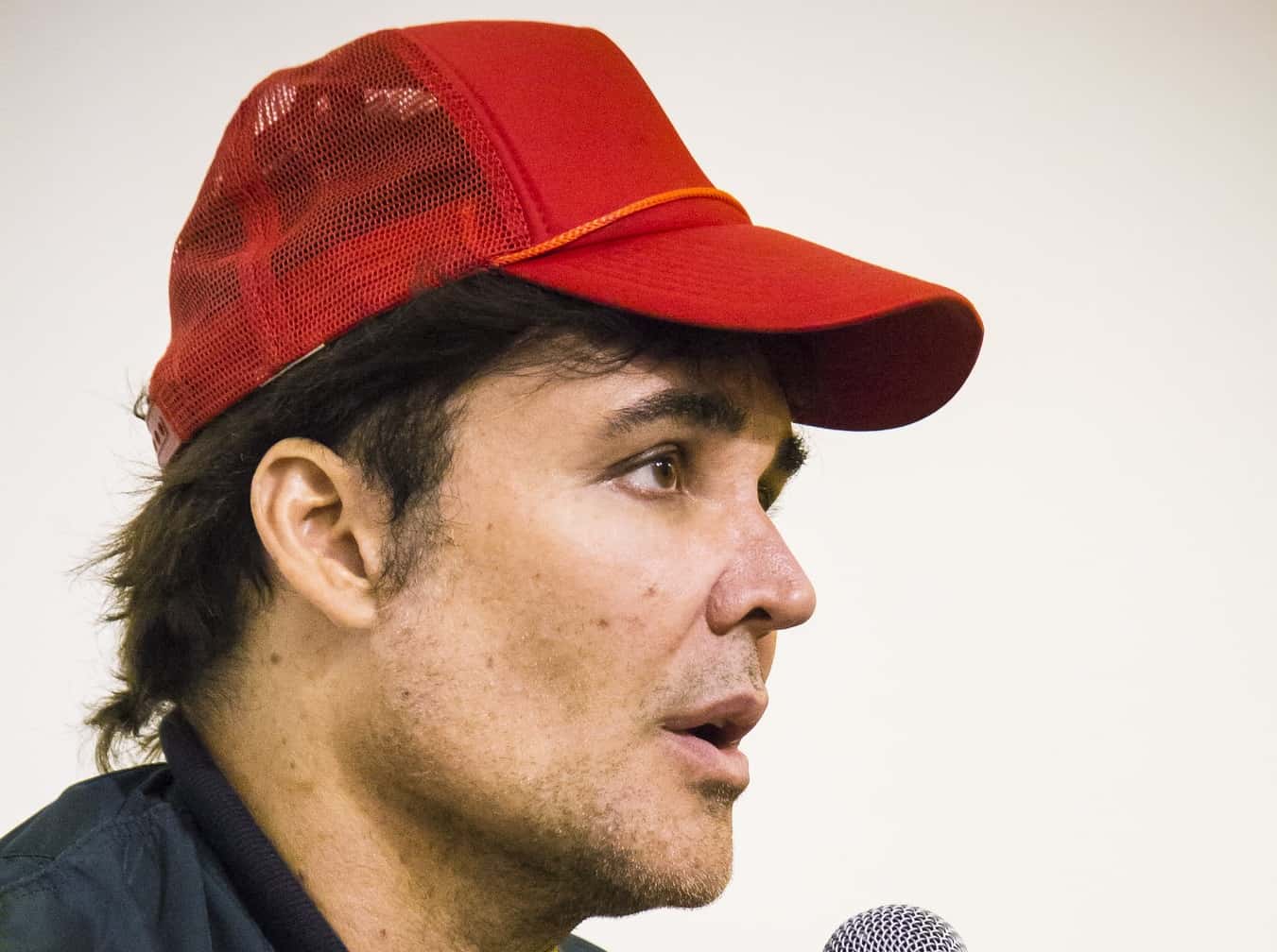 Portrait Photo of David LaChapelle wearing a black jacket and red hat