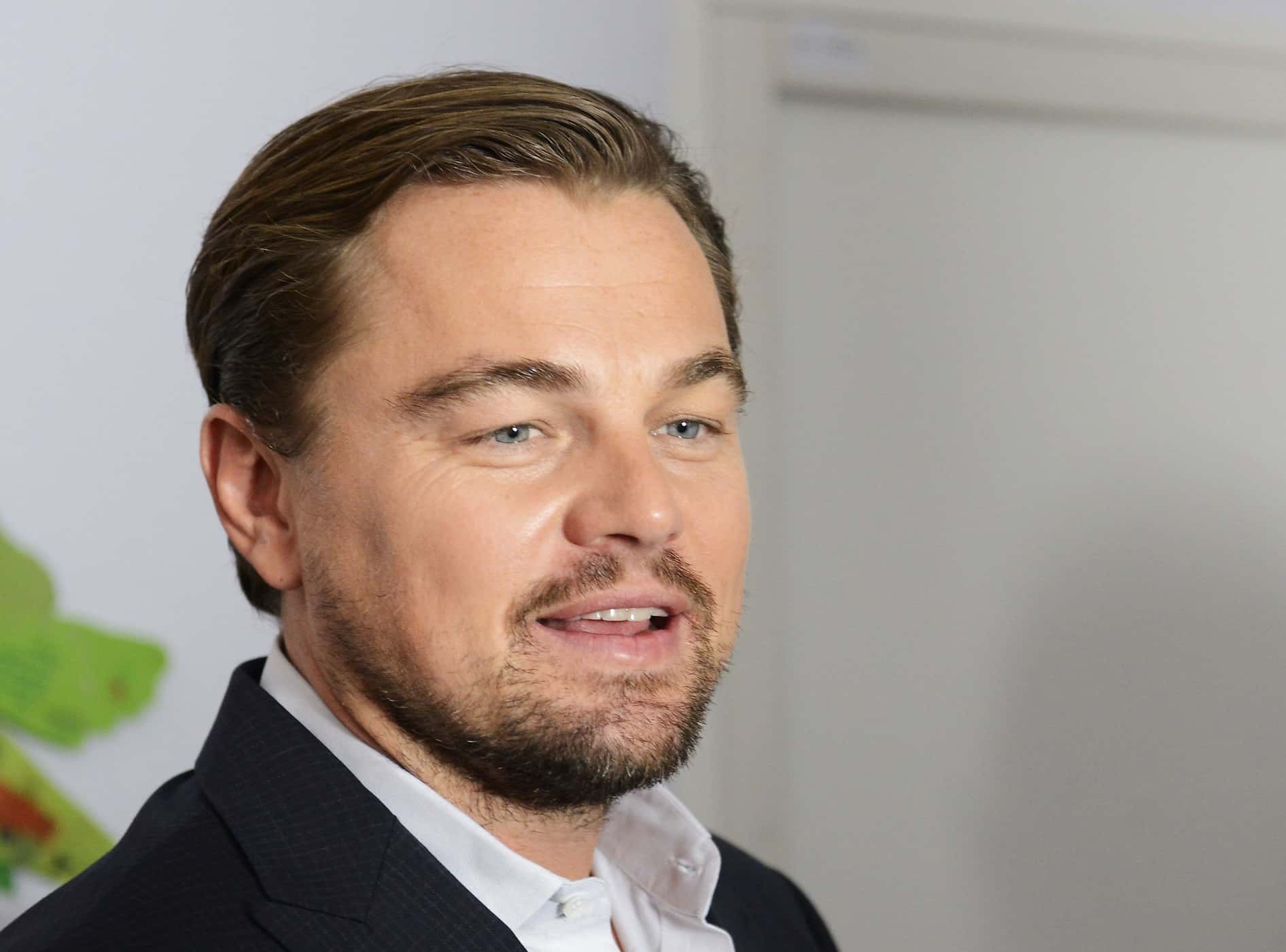 Portrait Photo of Leonardo di Caprio in a dark suit and white shirt, looking to the right