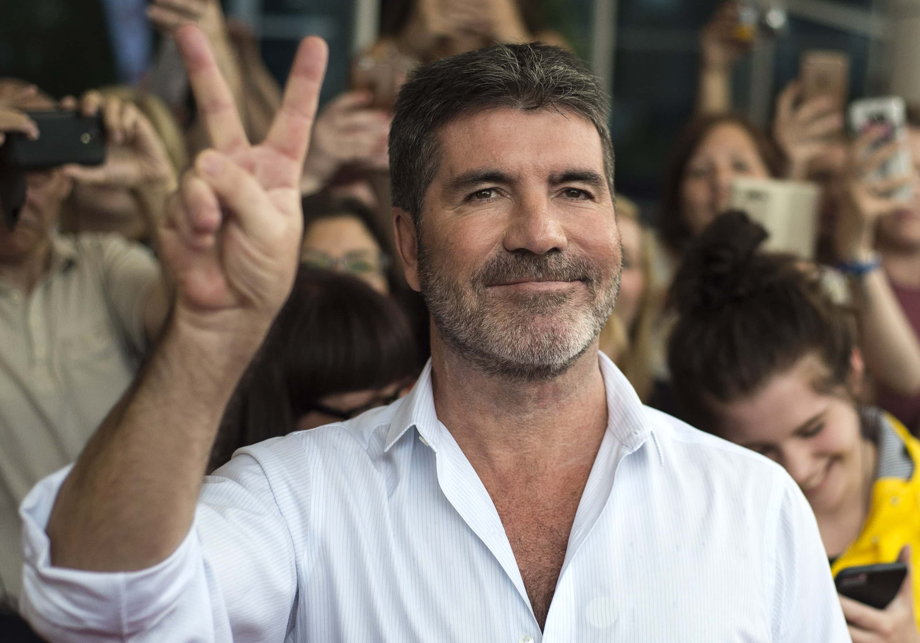 Simon Cowell in white shirt showing peace sign 
