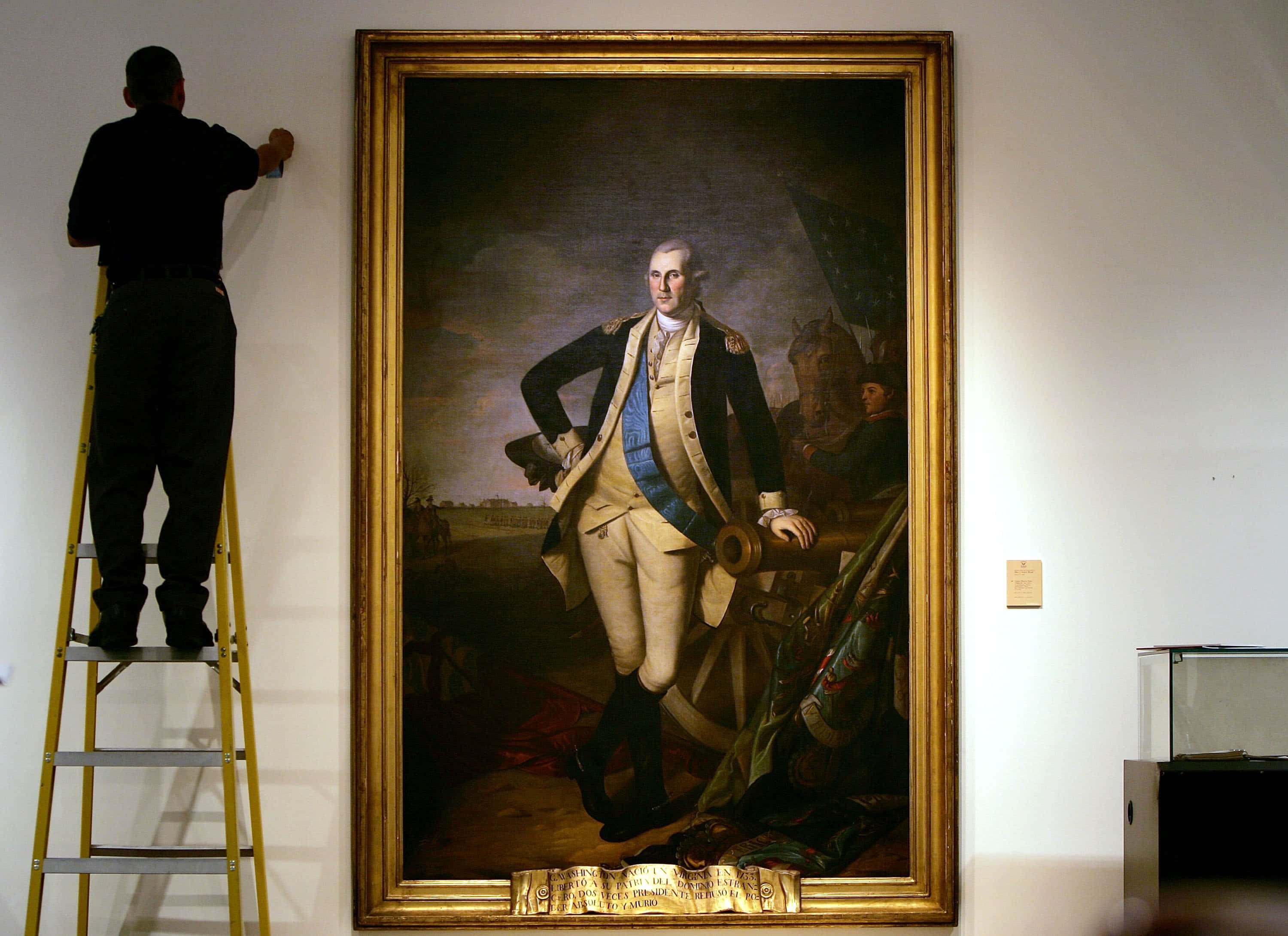 A worker uses a ladder to work near a full length portrait of former U.S. President George Washington - 2006