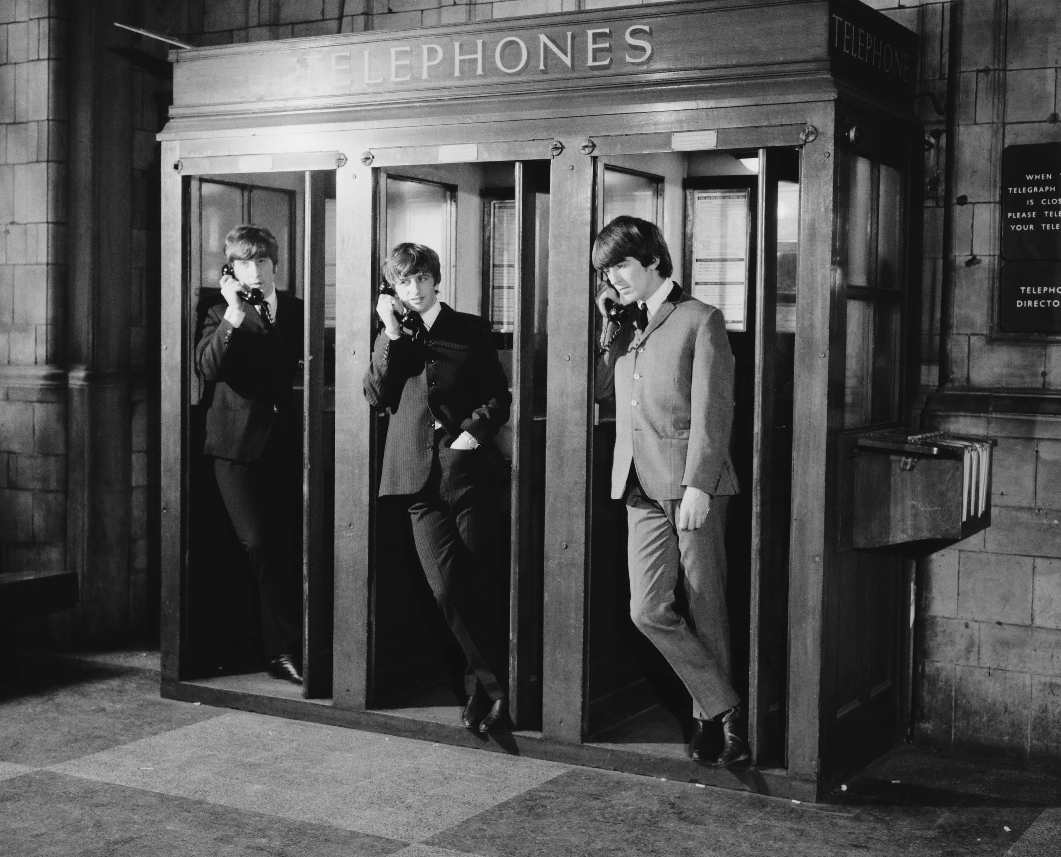 Singer John Lennon (1940 - 1980), drummer Ringo Starr, and guitarist George Harrison (1943 - 2001) in telephone kiosks at Marylebone Station