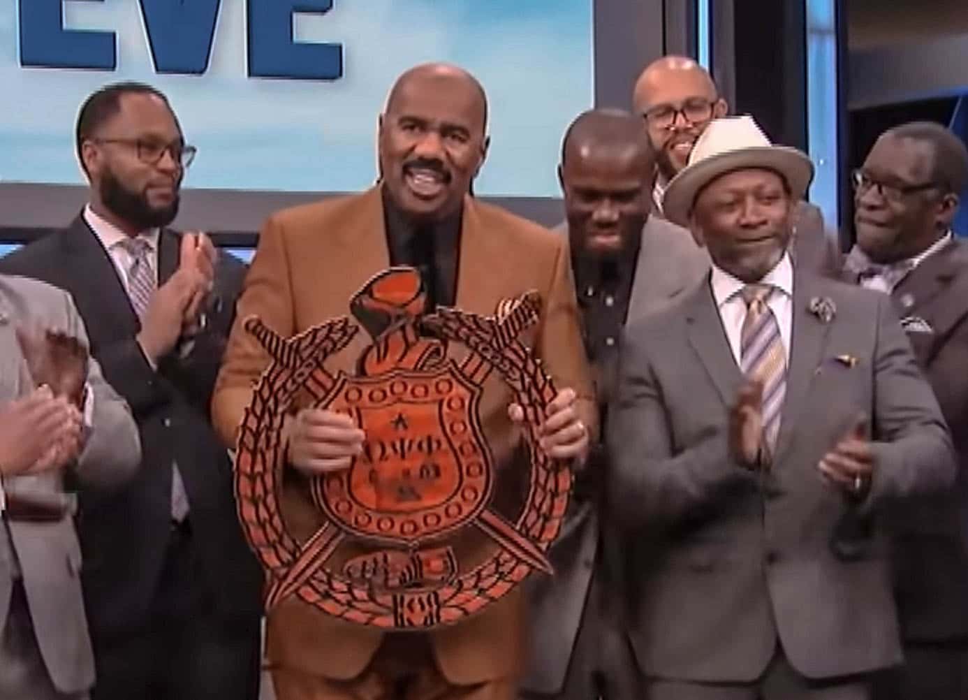 Screenshot of Steve Harvey holding a sign in studio - from Steve Harvey (1996/2002)