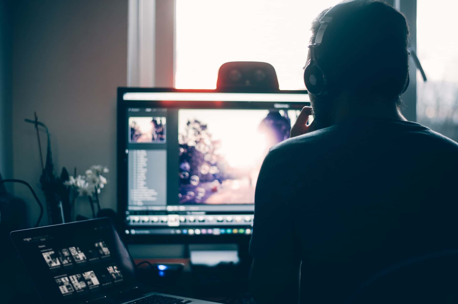 Person with headphone on his head sitting in front of a monitor and other computer equipment