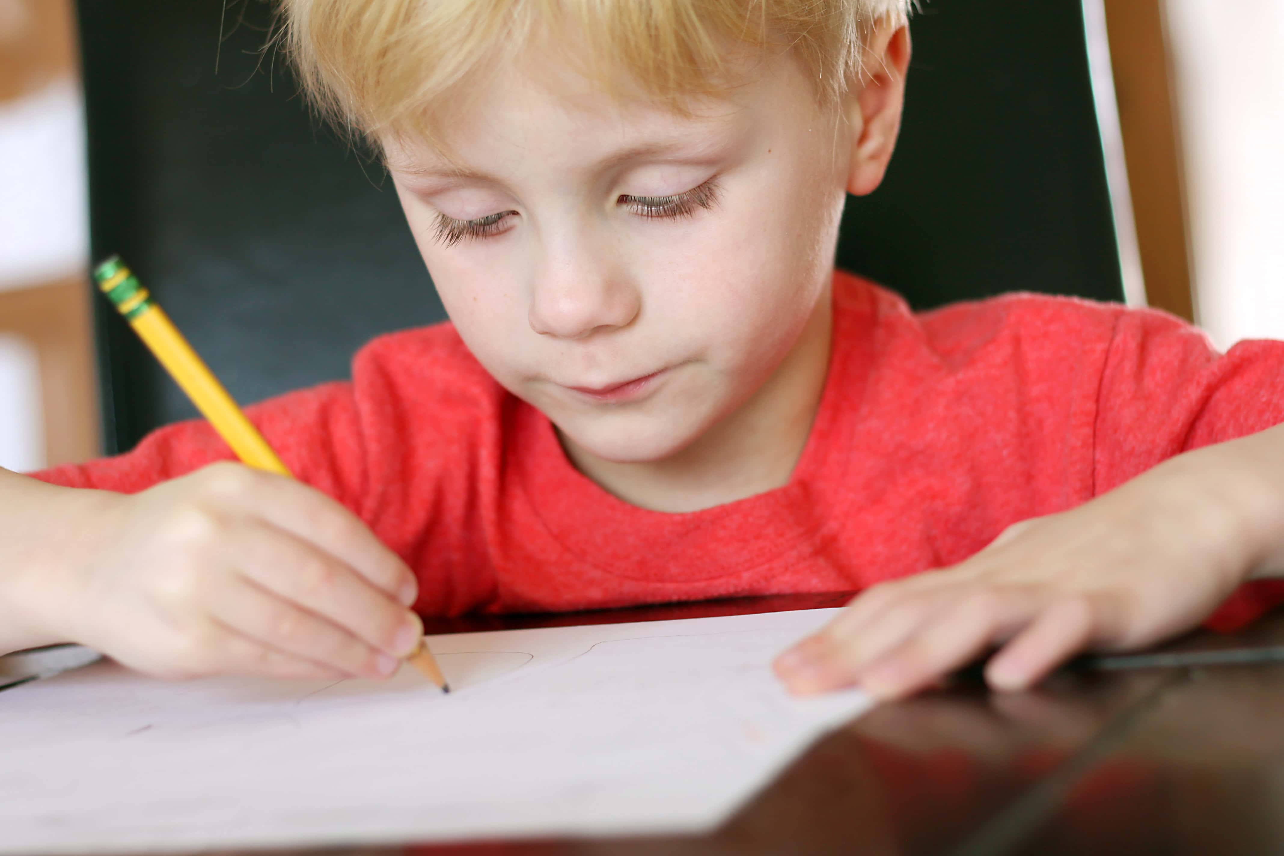 Пишем историю школы. Прилежный ребенок. Ребенок пишет. Писающий мальчик. Мальчик пишет в тетради.