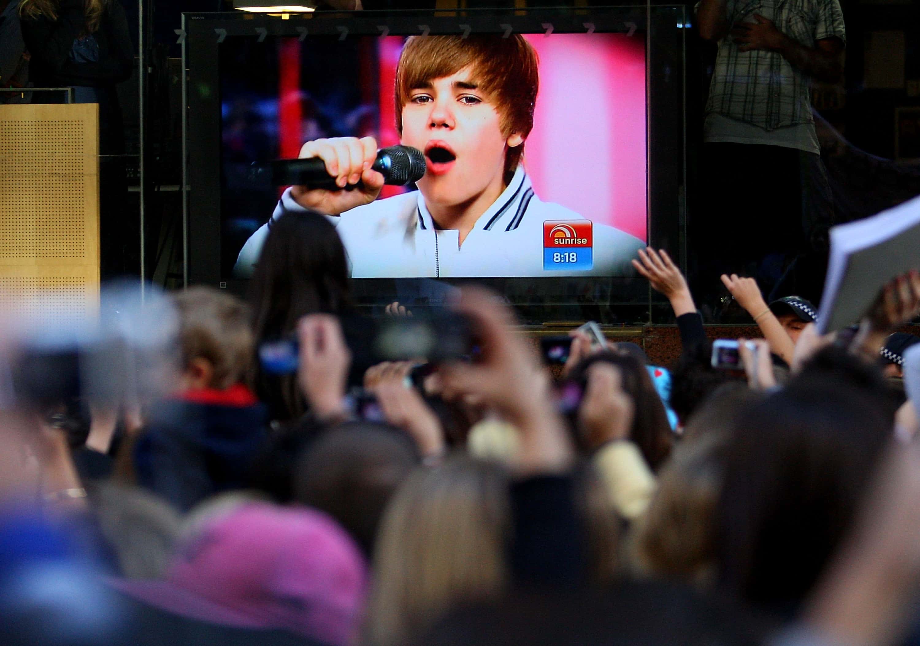 A large crowd of Justin Bieber fans watch the singers performance on a screen during the 