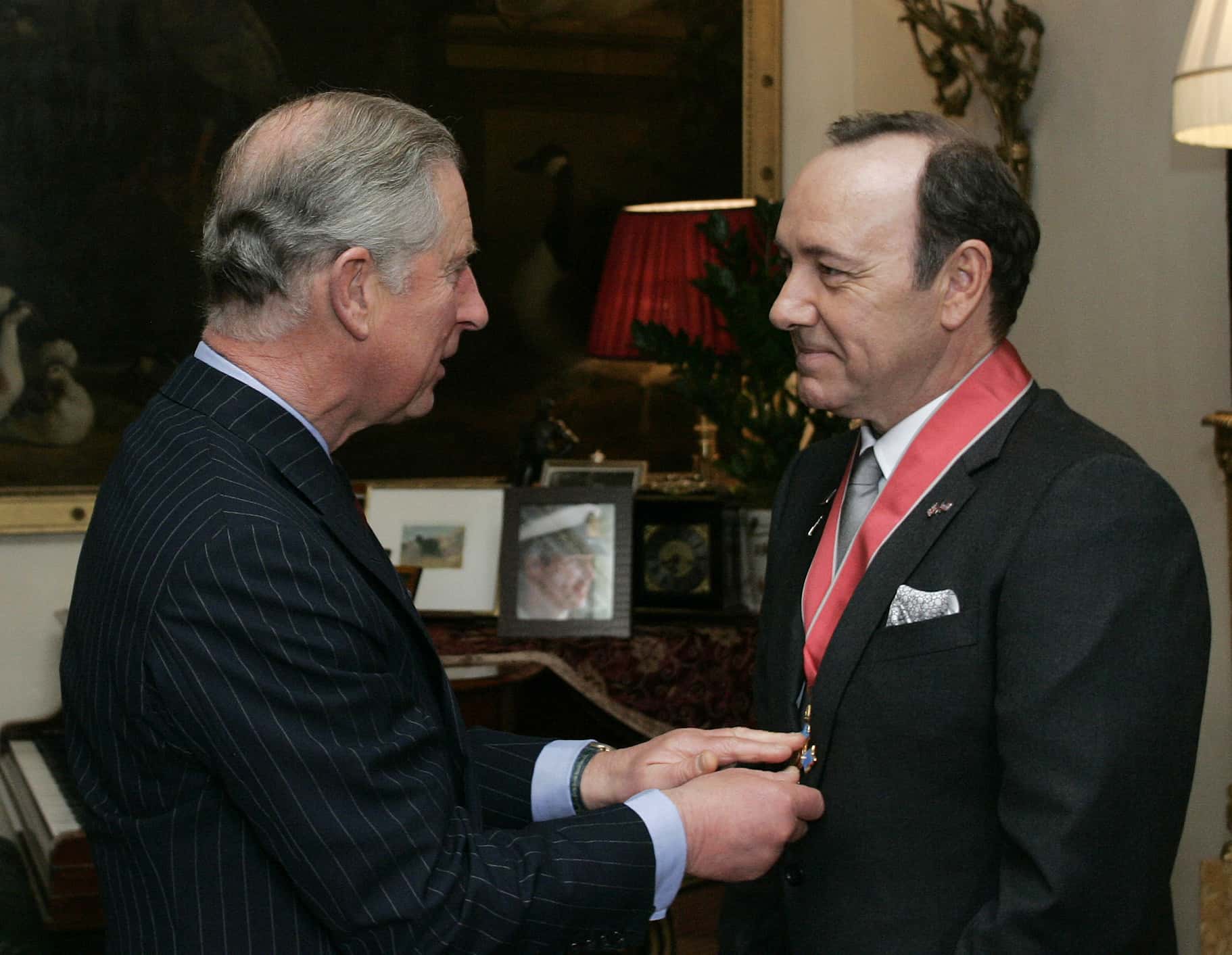 Actor Kevin Spacey (R) is presented with his honorary CBE (Commander of the British Empire) medal for services to drama by Prince Charles