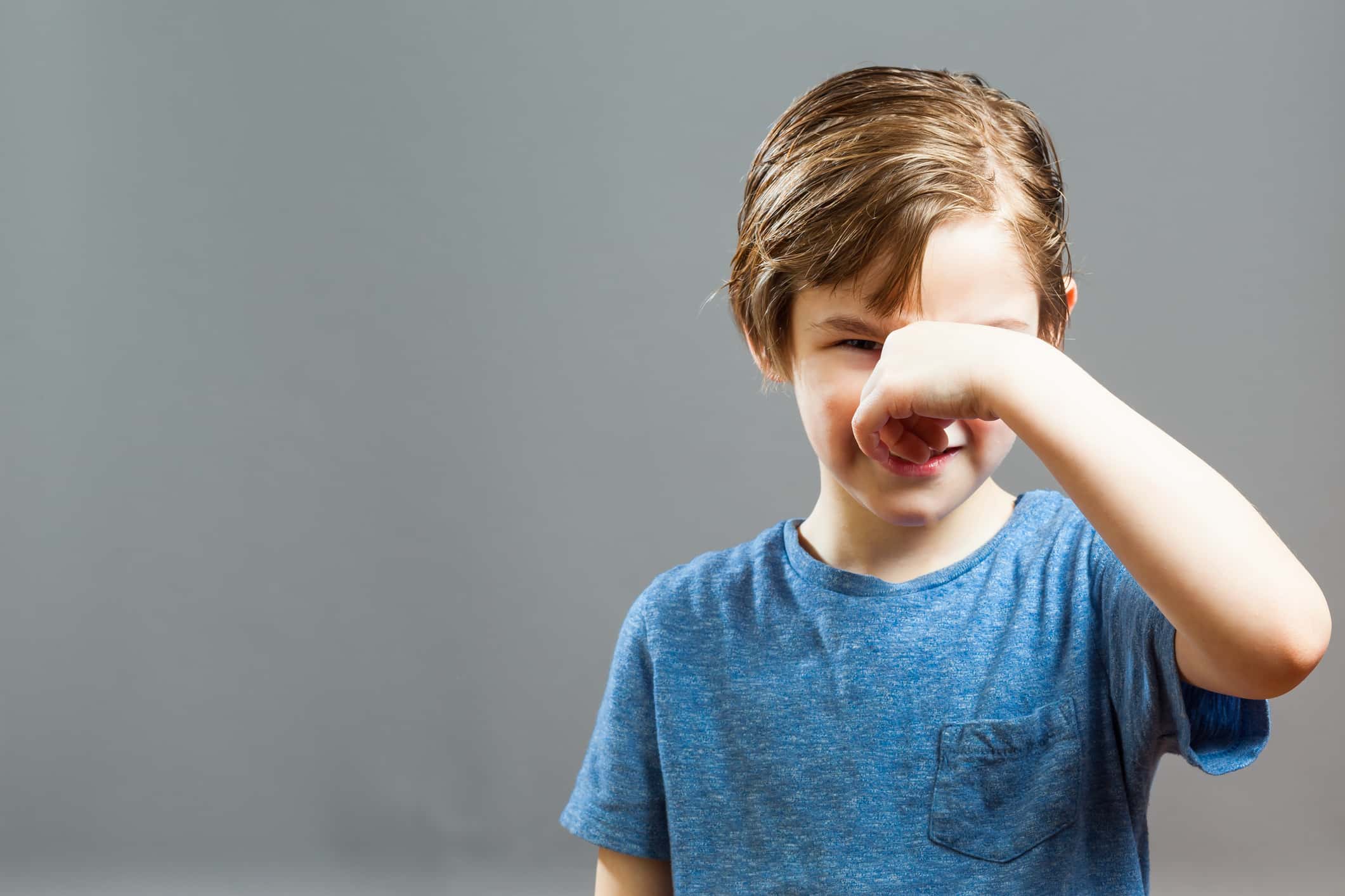 Boy Holding Nose While Standing Against Wall At Home