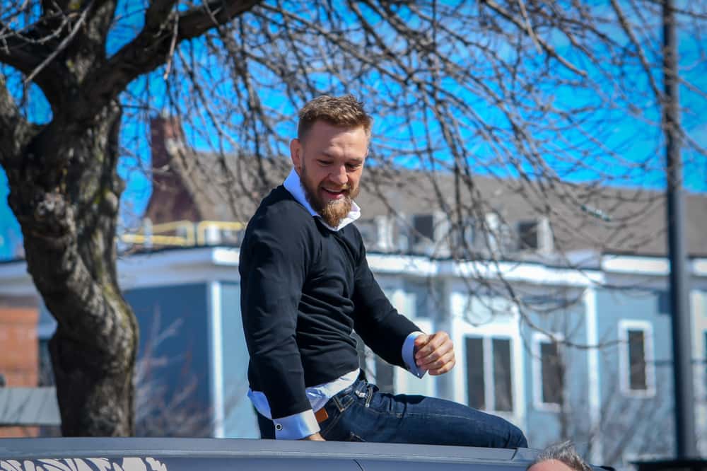 Conor McGregor sitting on top of a car