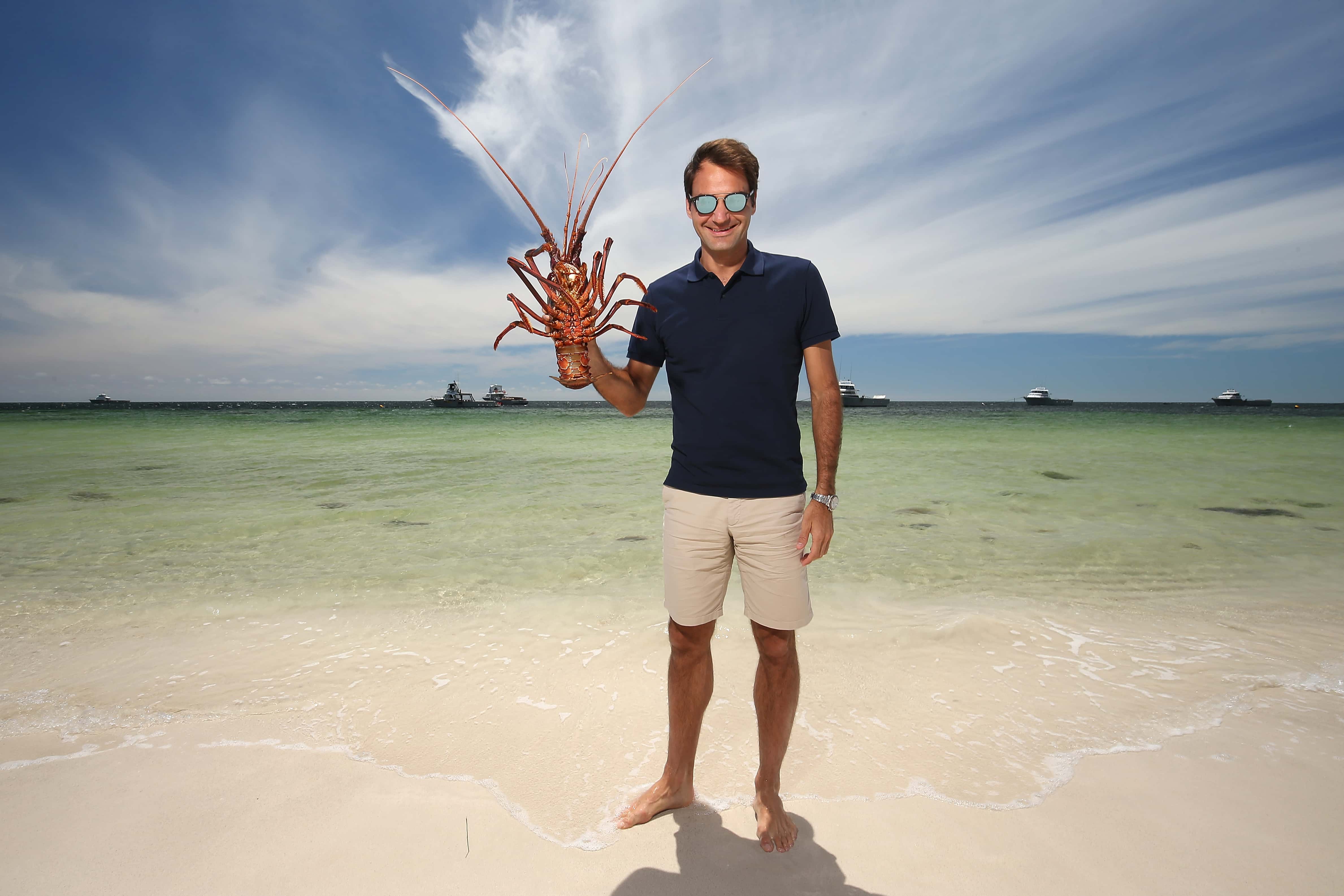 Roger Federer holds a Western Rock Lobster on the beach at The Lobster Shack