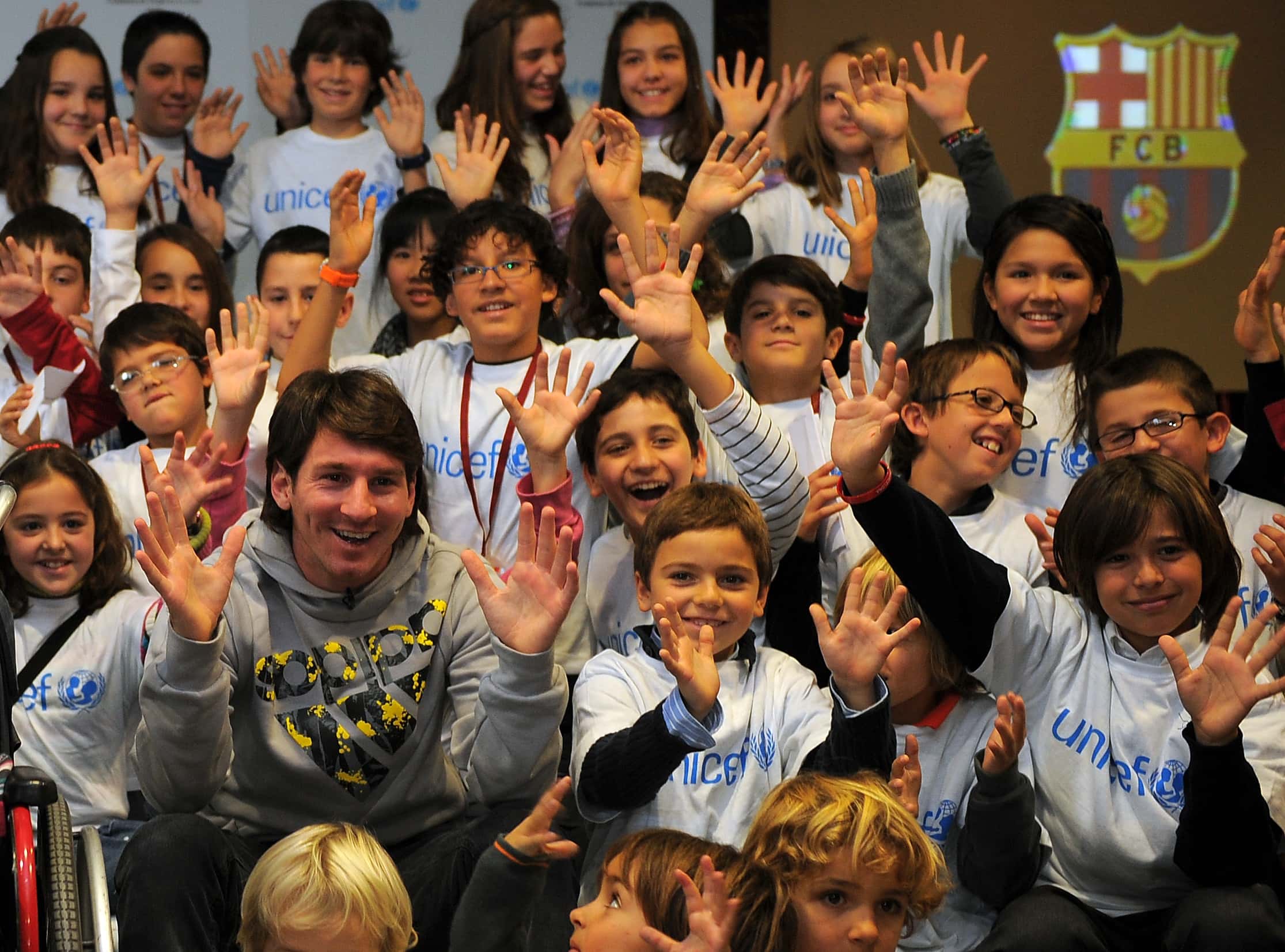 Unicef Ambassador and Barcelona's Argentinian forward Lionel Messi waves along with children
