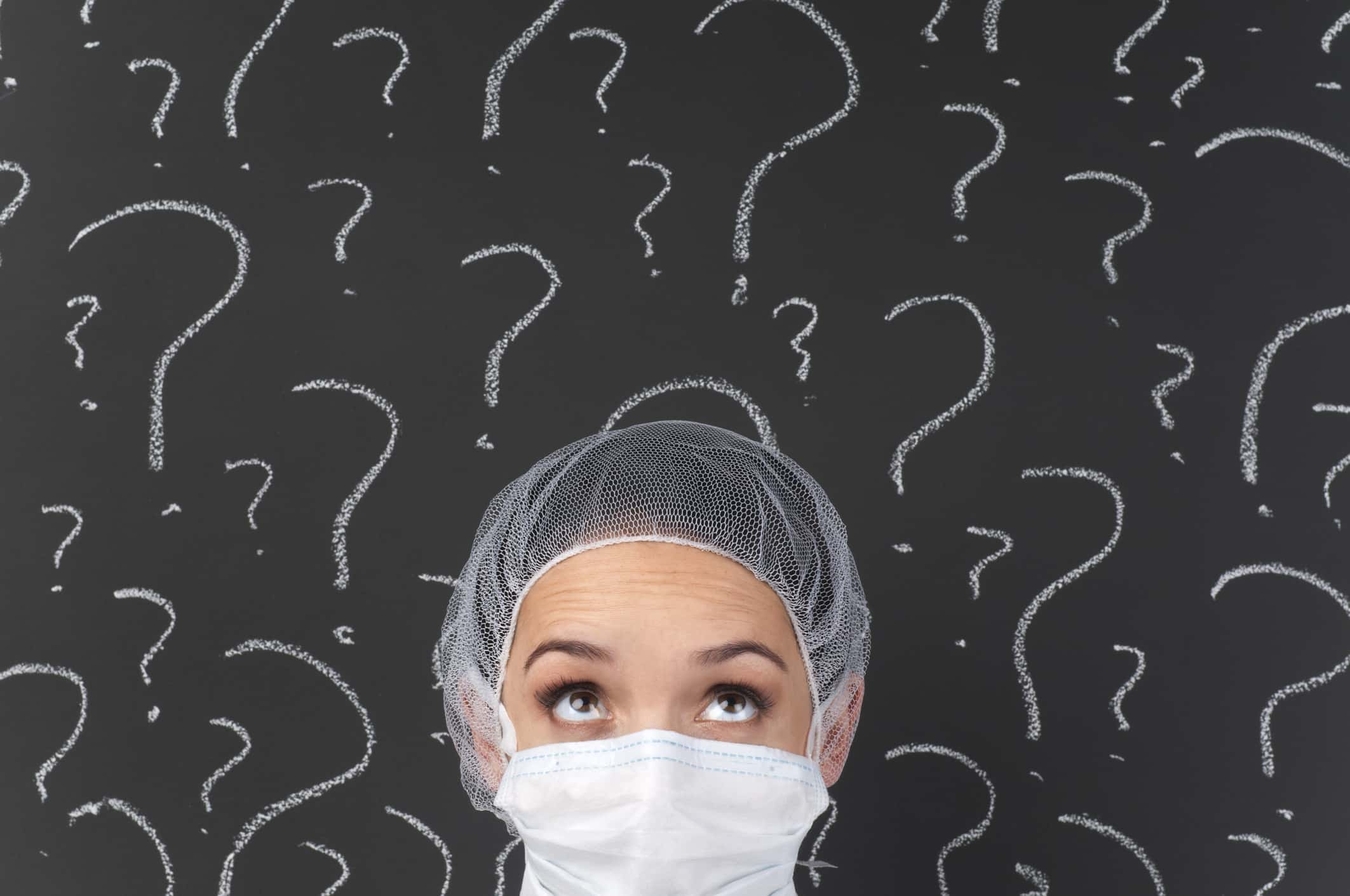 Female doctor thinking in front of question marks