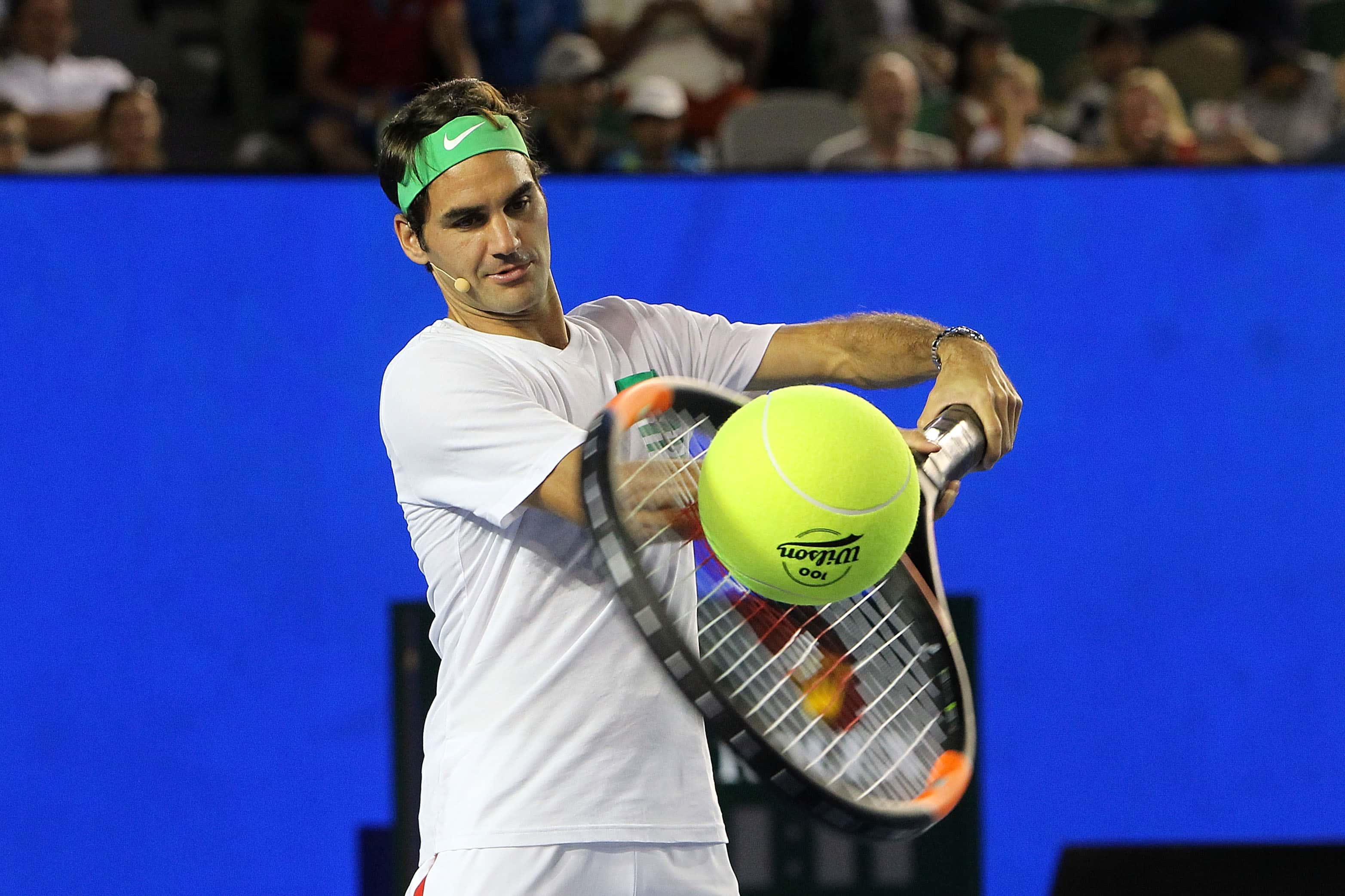 Roger Federer of Switzerland plays with a giant ball and racquet