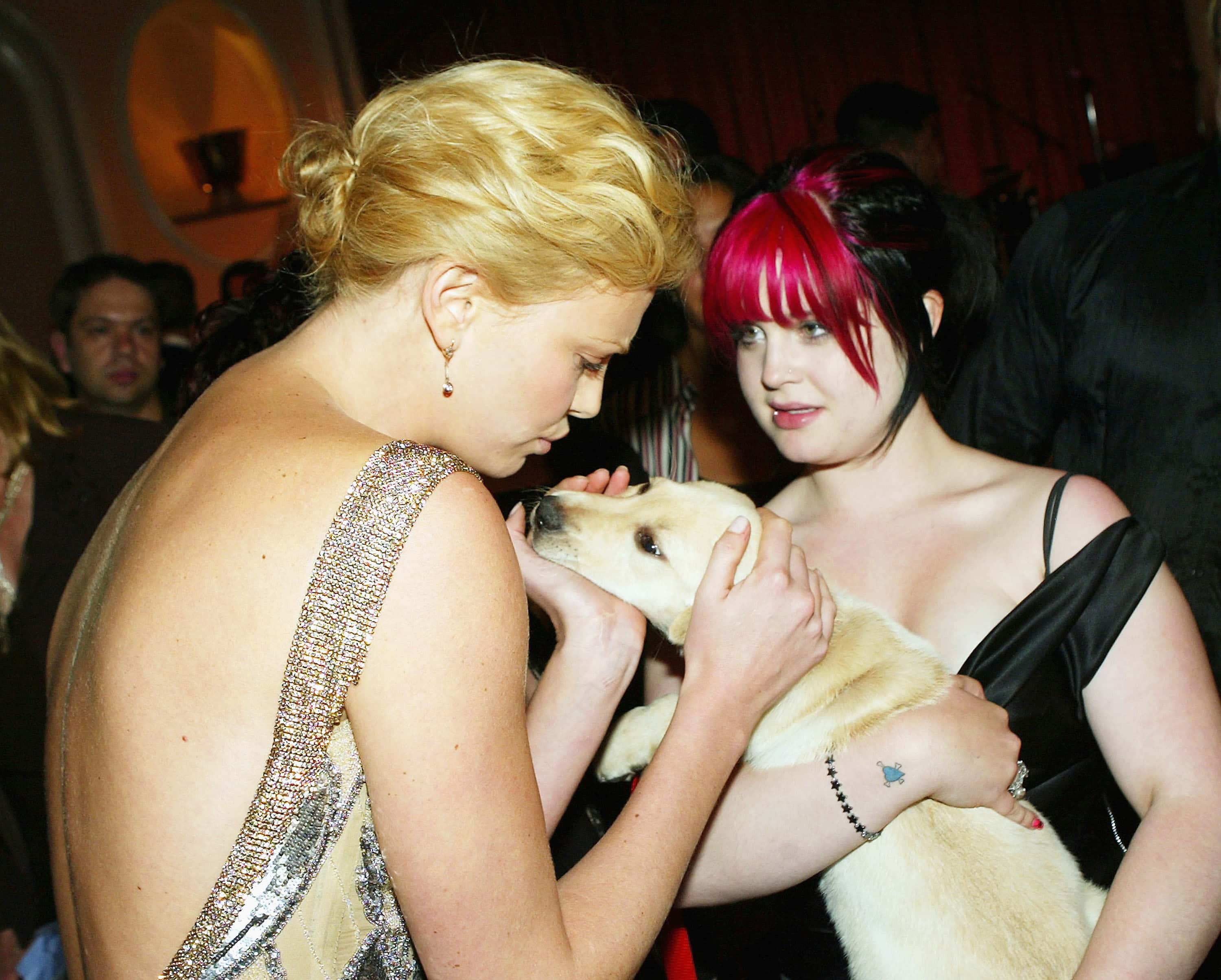 Actress Charlize Theron (L) pets a puppy