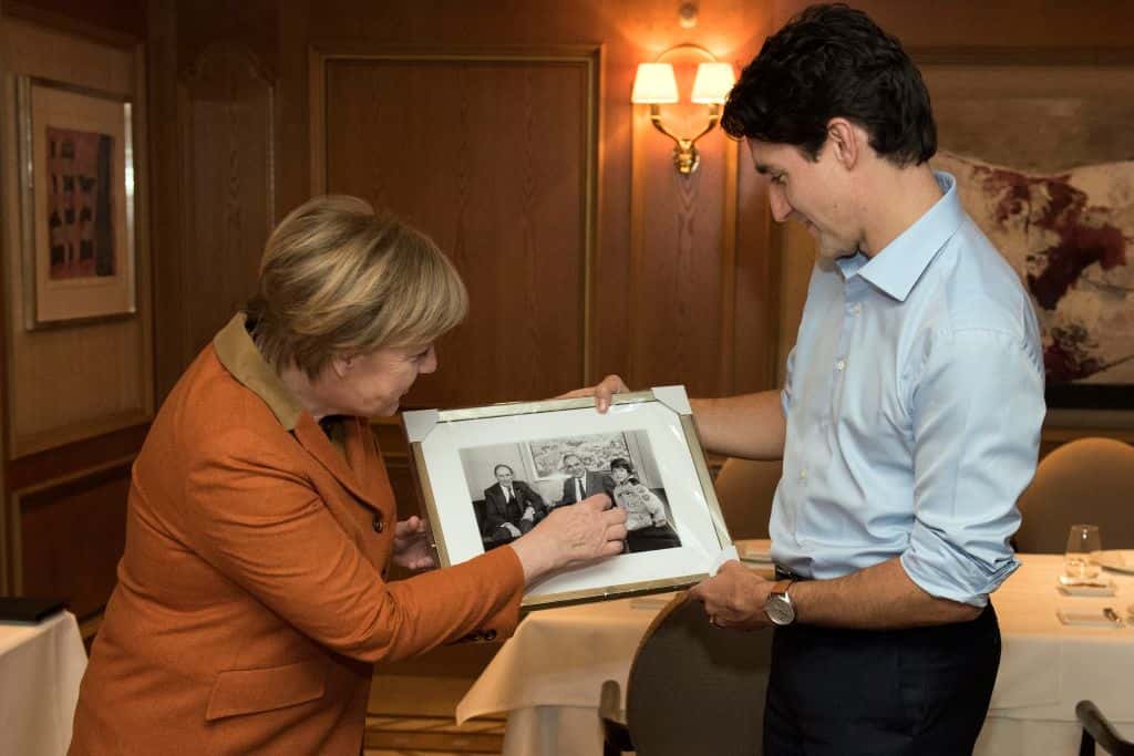 German Chancellor Angela Merkel presents a photo to Canadian Prime Minister Justin Trudeau which shows him posing with his father Pierre Trudeau