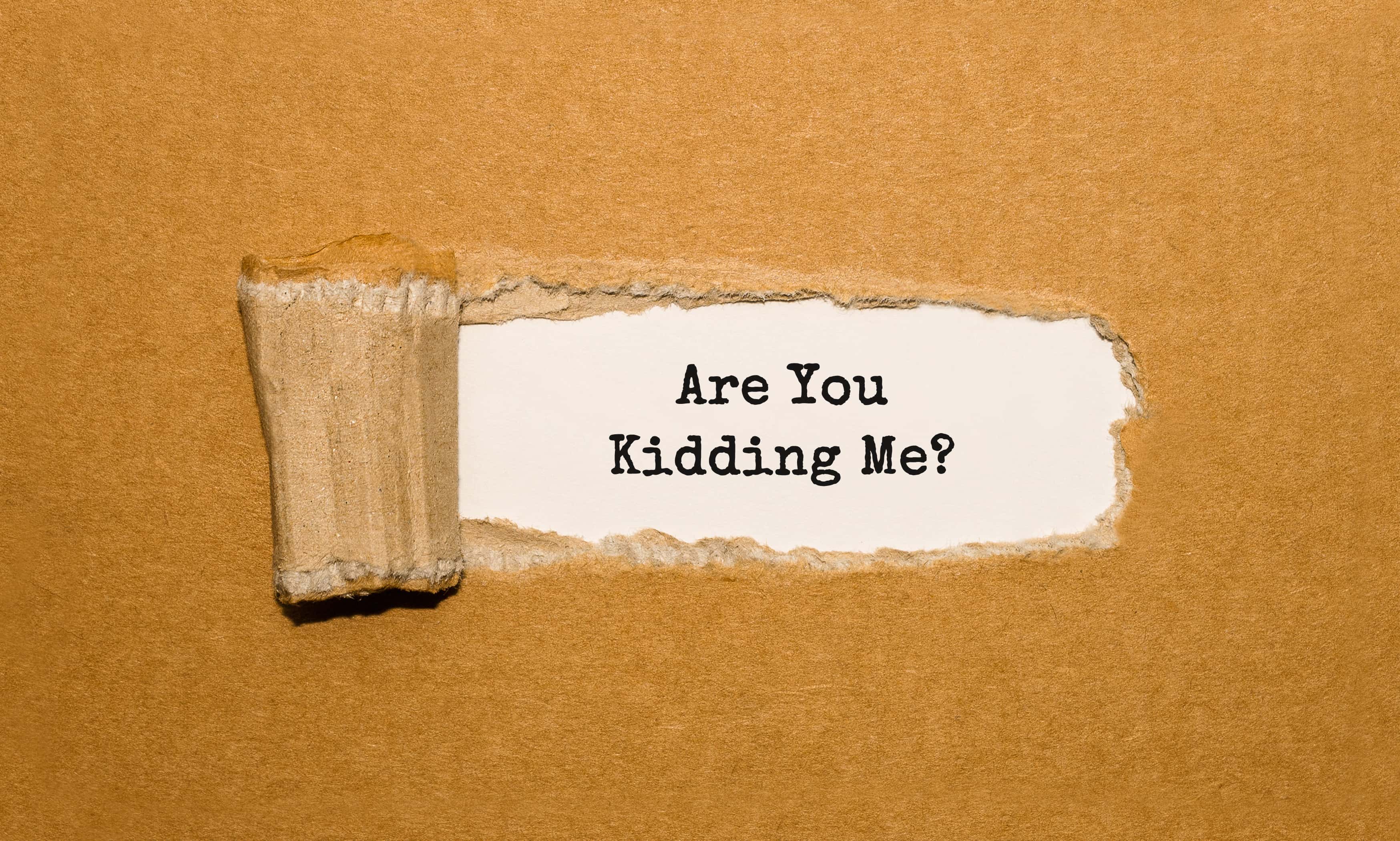 re You Kidding Me appearing behind torn brown paper