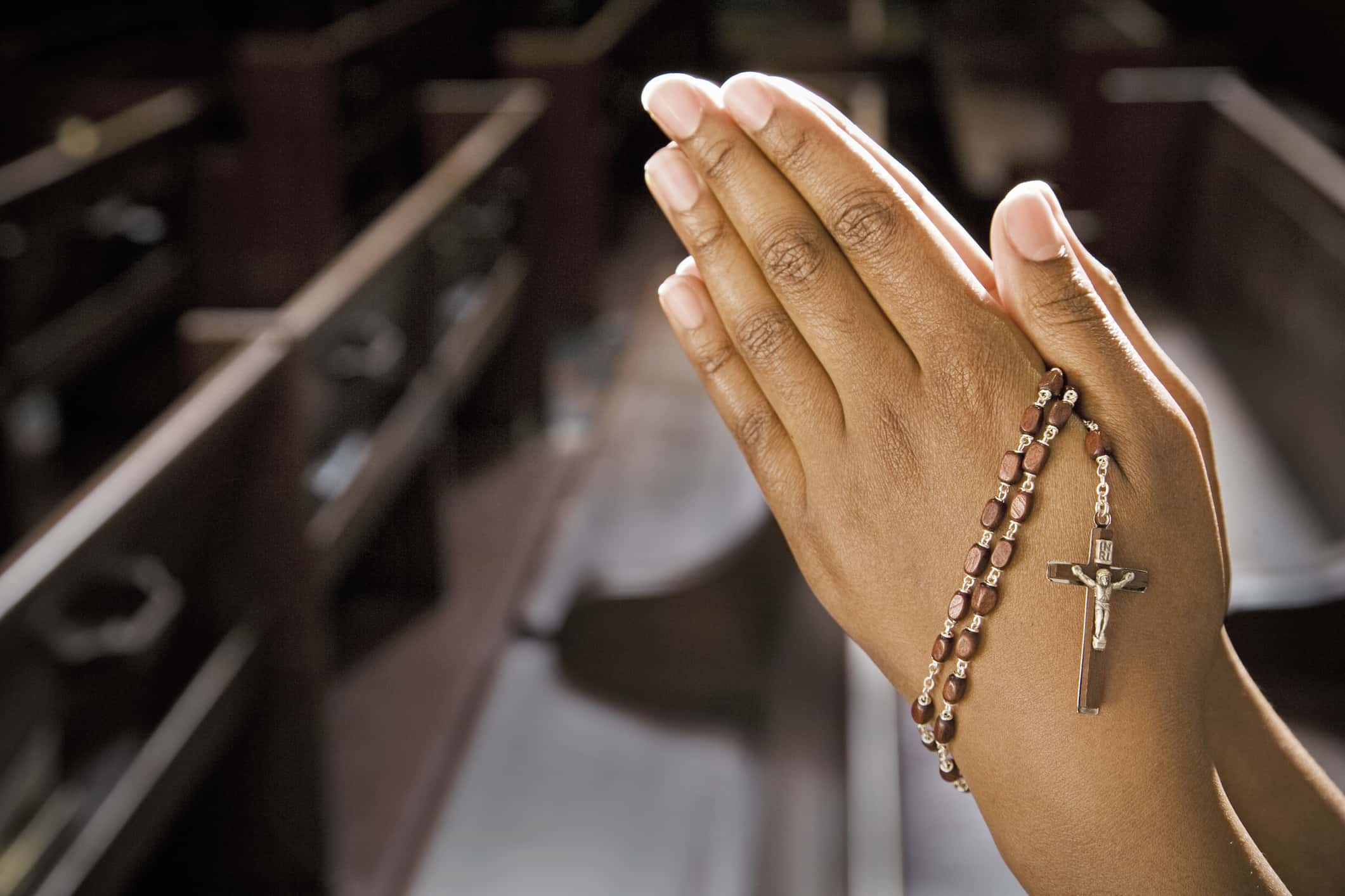 Hands Praying in Church With Rosary.
