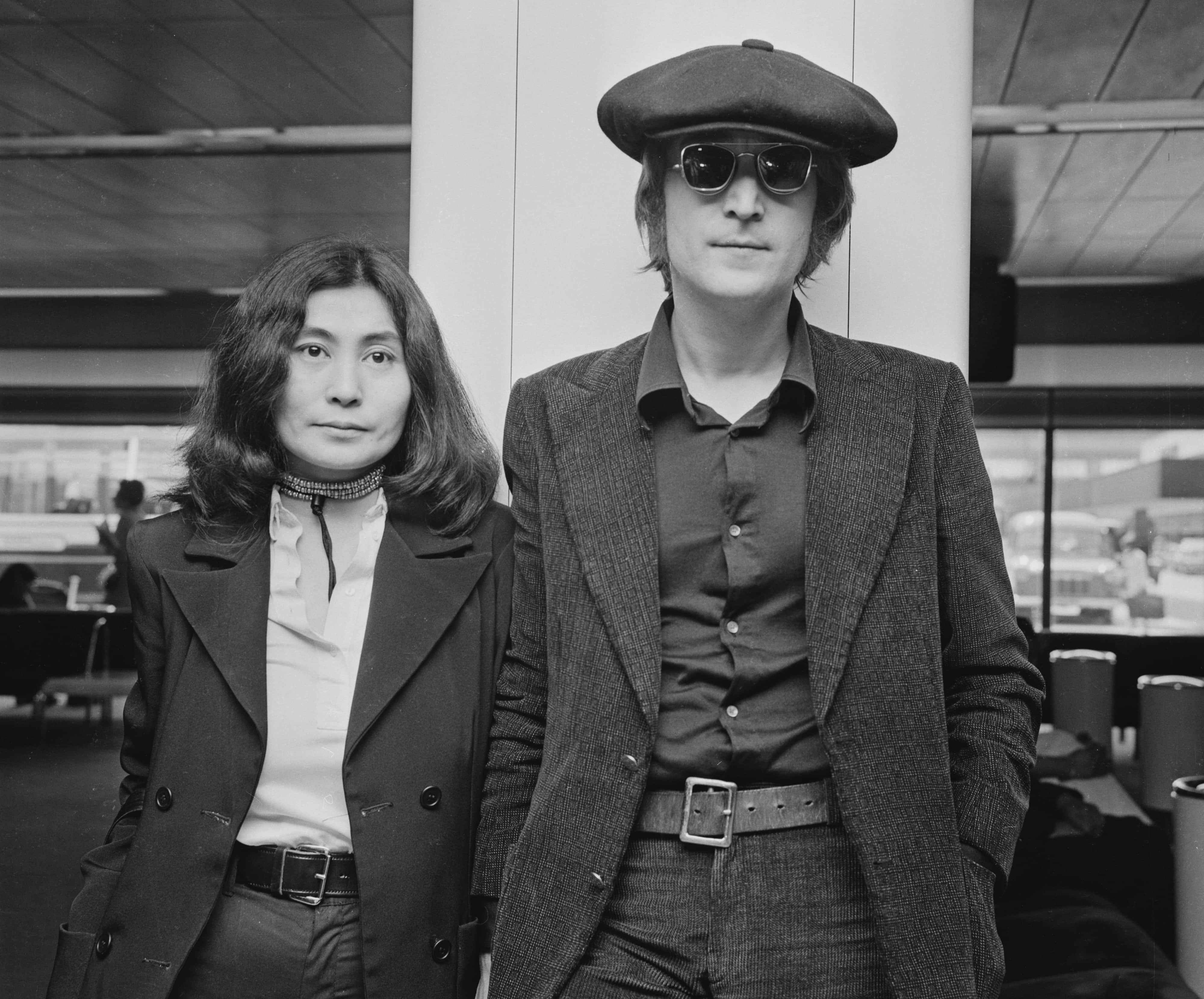 John Lennon (1940 - 1980) and his wife Yoko Ono arrive at London Airport