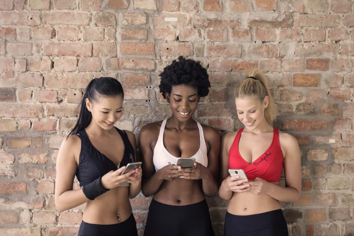 beautiful_blonde_brick_wall_cellphone_diversity_female_fit_friends-1559235
